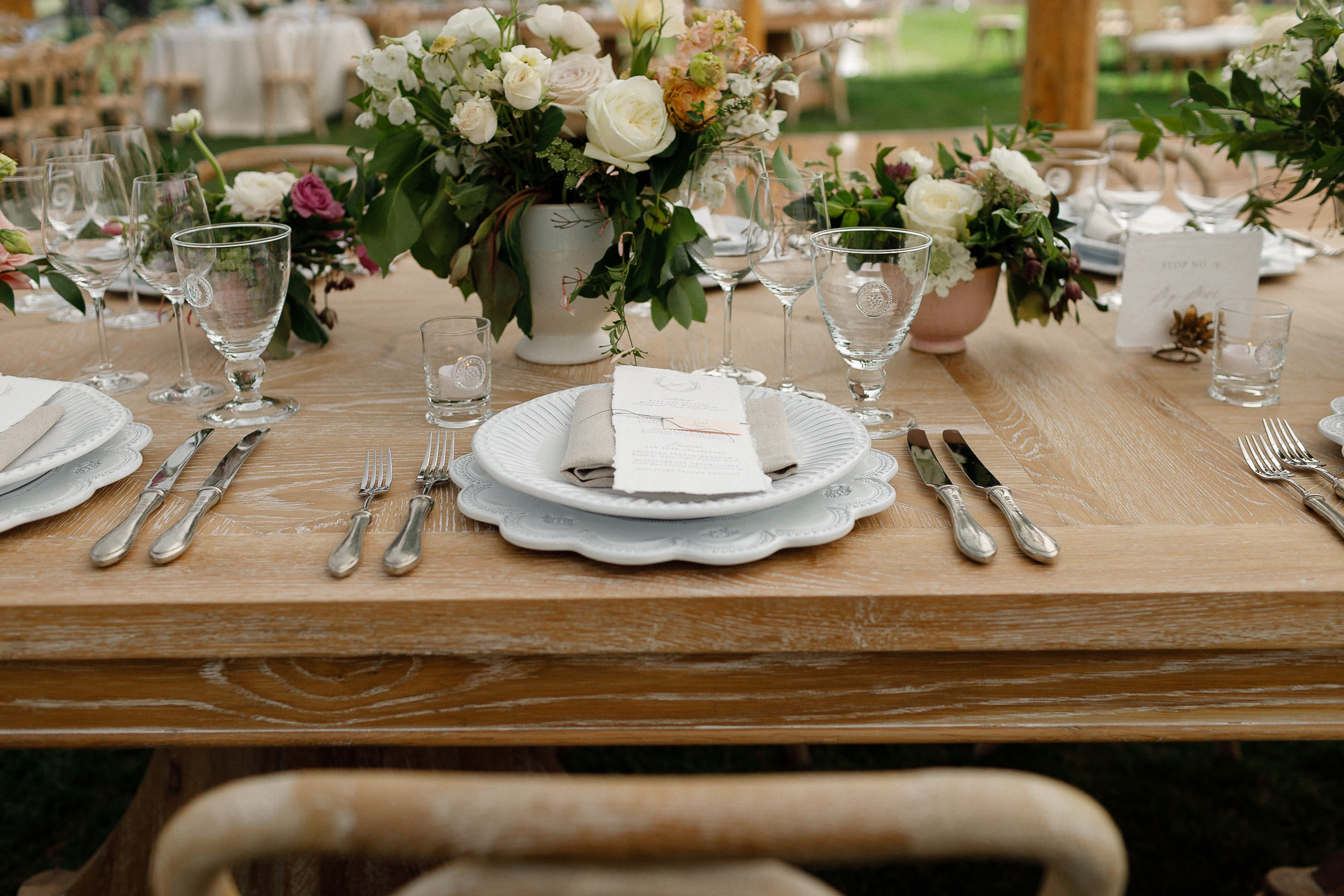 A formal table at The Ritz-Carlton, Lake Tahoe, with plates, silverware, wine glasses, and white and pink floral centerpieces.