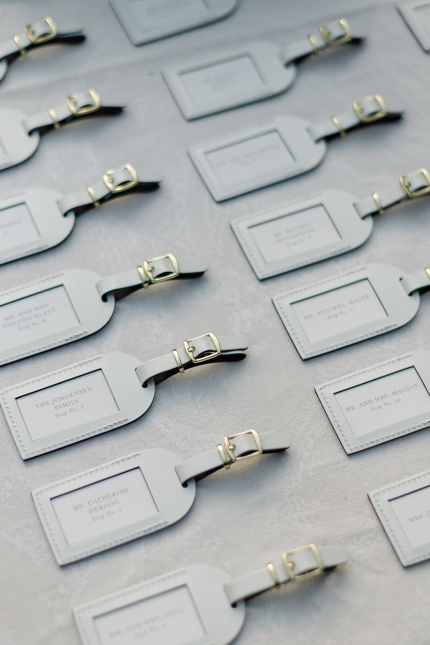 White luggage tags with gold buckles, each labeled with a name and table number, serve as Lake Tahoe wedding escort cards.