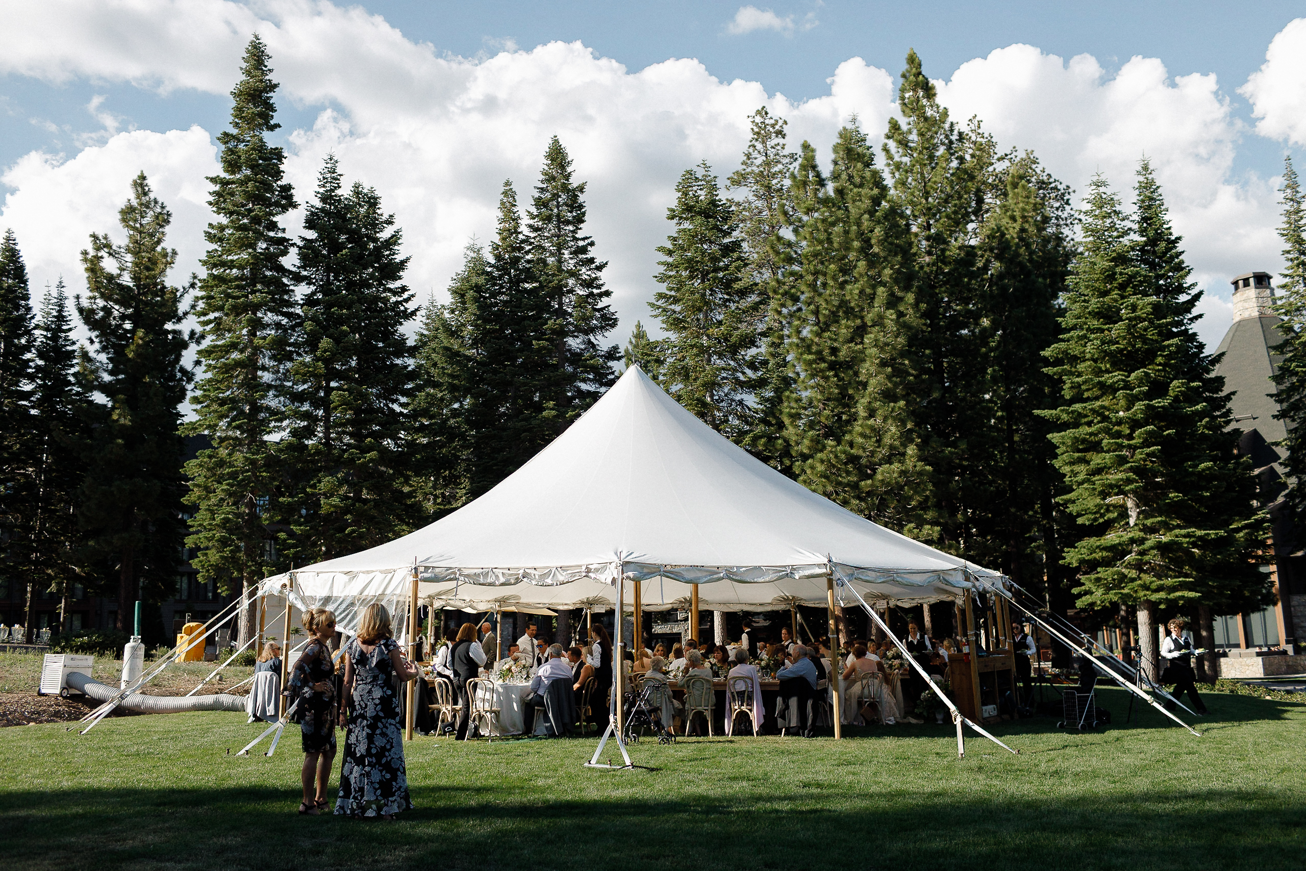 Large white tent on grass at Ritz-Carlton Lake Tahoe, surrounded by pines. Guests sit inside; some stand outside. Planned by Elise Events.
