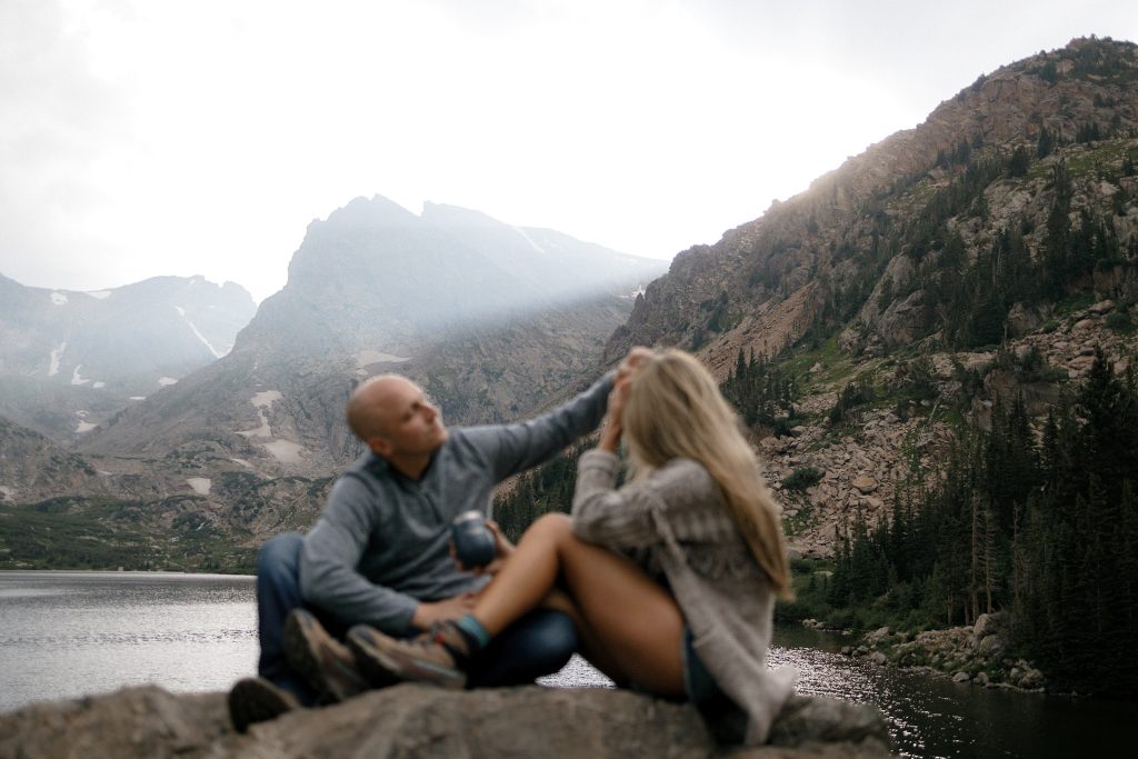 San Francisco engagement by mountain lake, sunlit peaks and forested slopes. Romantic valley setting.