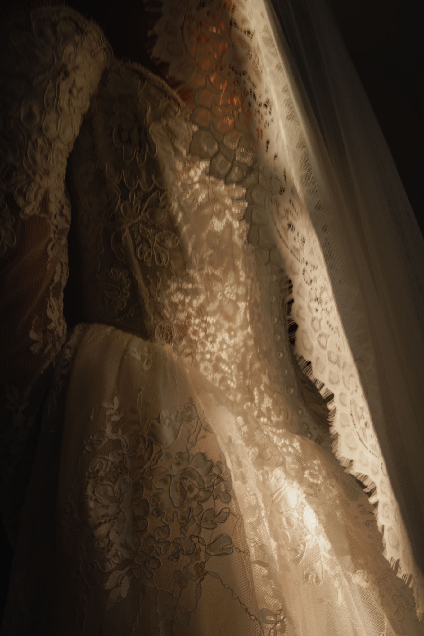 Close-up of a white lace wedding dress and veil at Woodhill Park Estate, showing detailed floral patterns and fabric textures.