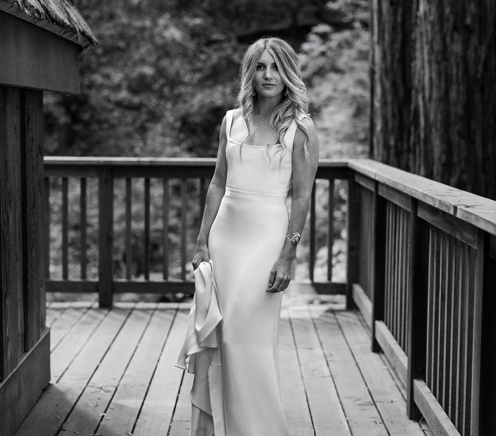 Elegant bride in timeless white dress on woodland deck, capturing serene bridal beauty.