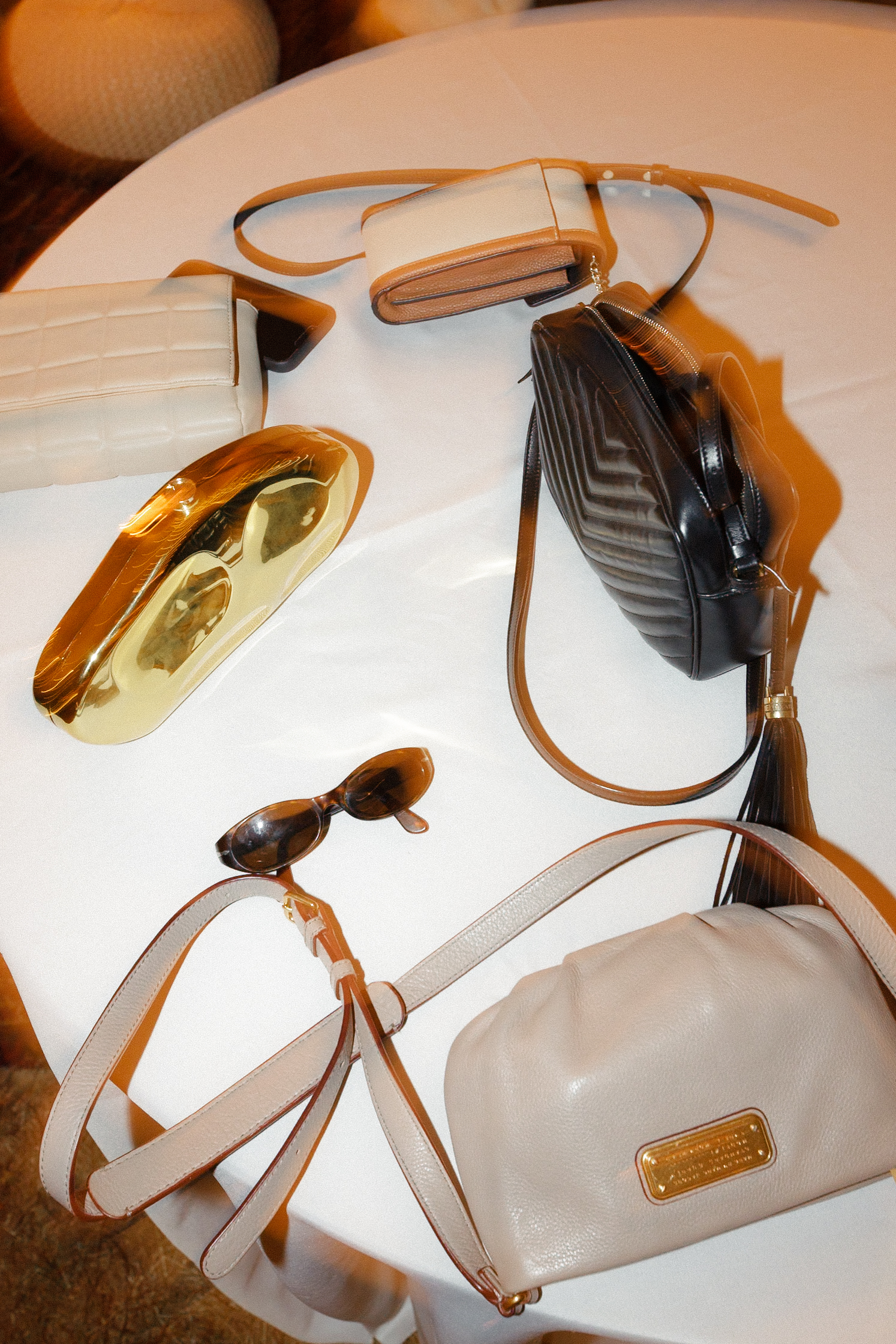 High-end wedding accessories: handbags, Cuffey Cove sunglasses, wallets with gold details; warm California ambiance.
