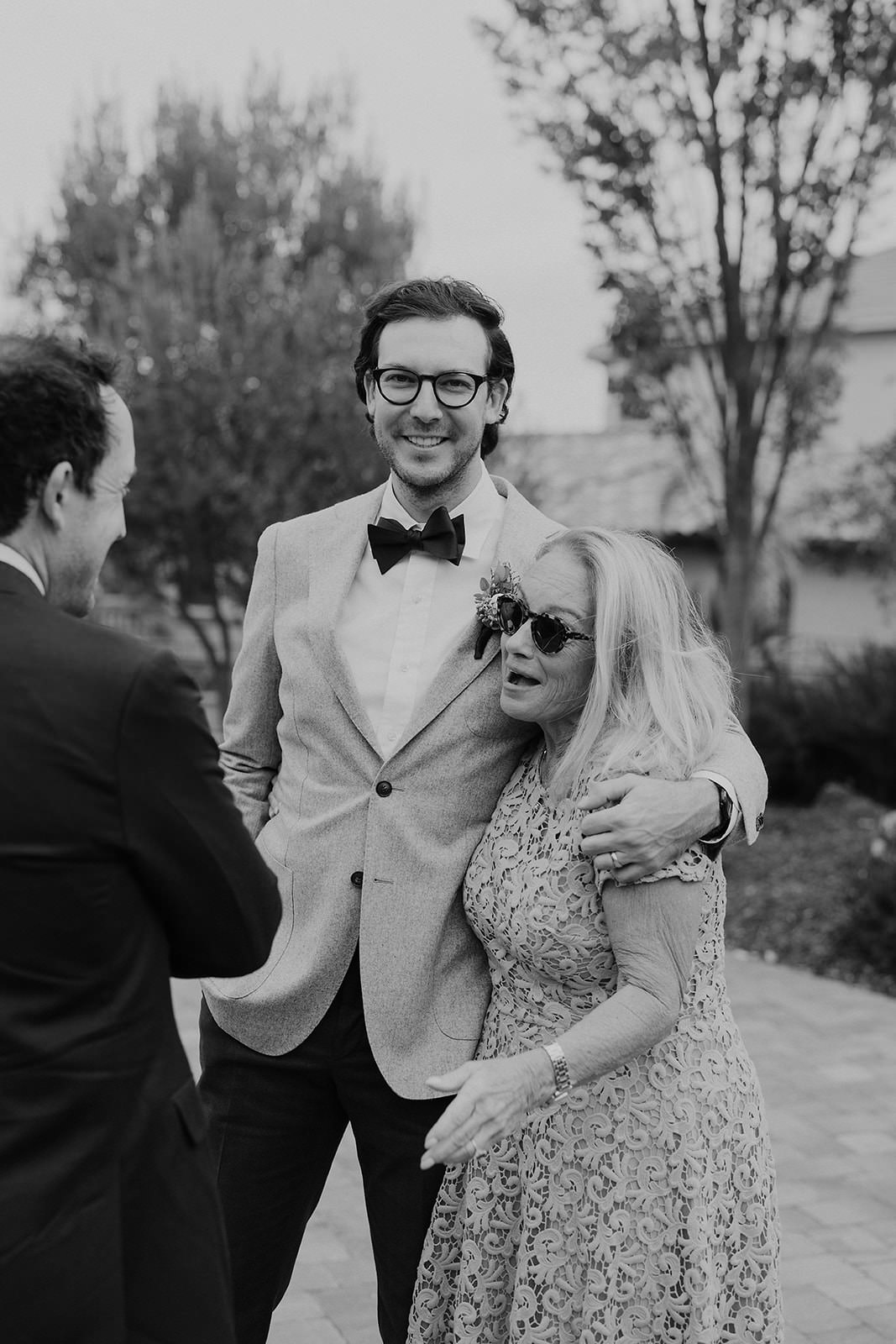 Elegant San Jose Wedding: Gentlemen in Suits with Smiling Companion, Outdoor Lively Backdrop.