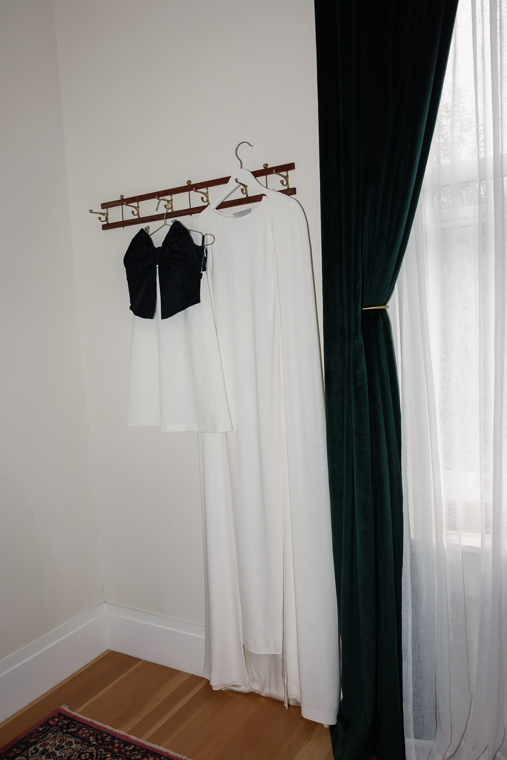 Mendocino Wedding Attire: White Dress & Black-and-White Top on Wooden Rack in Sunlit Room.