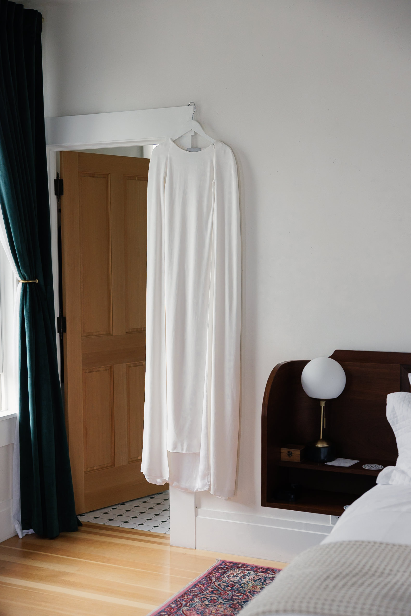 Elegant wedding gown in charming Mendocino room, coastal light through curtains, wood floors.