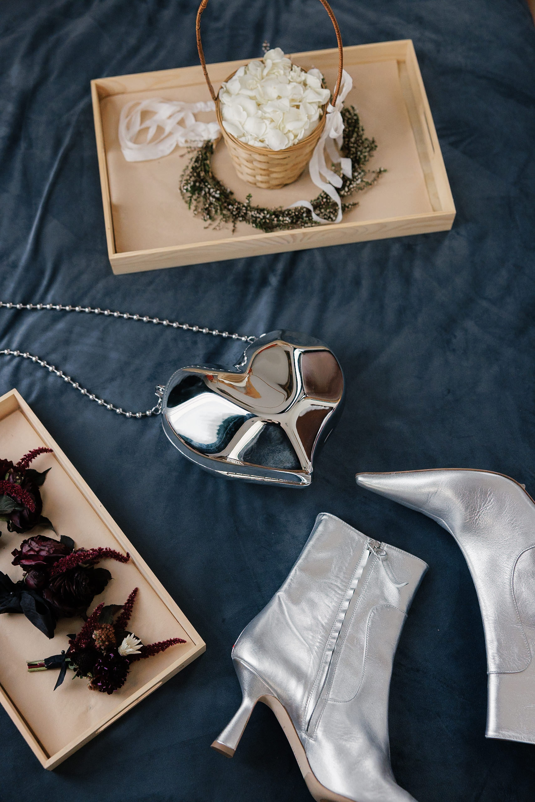 Elegant silver heeled boots and heart purse on dark fabric with white roses in Mendocino.