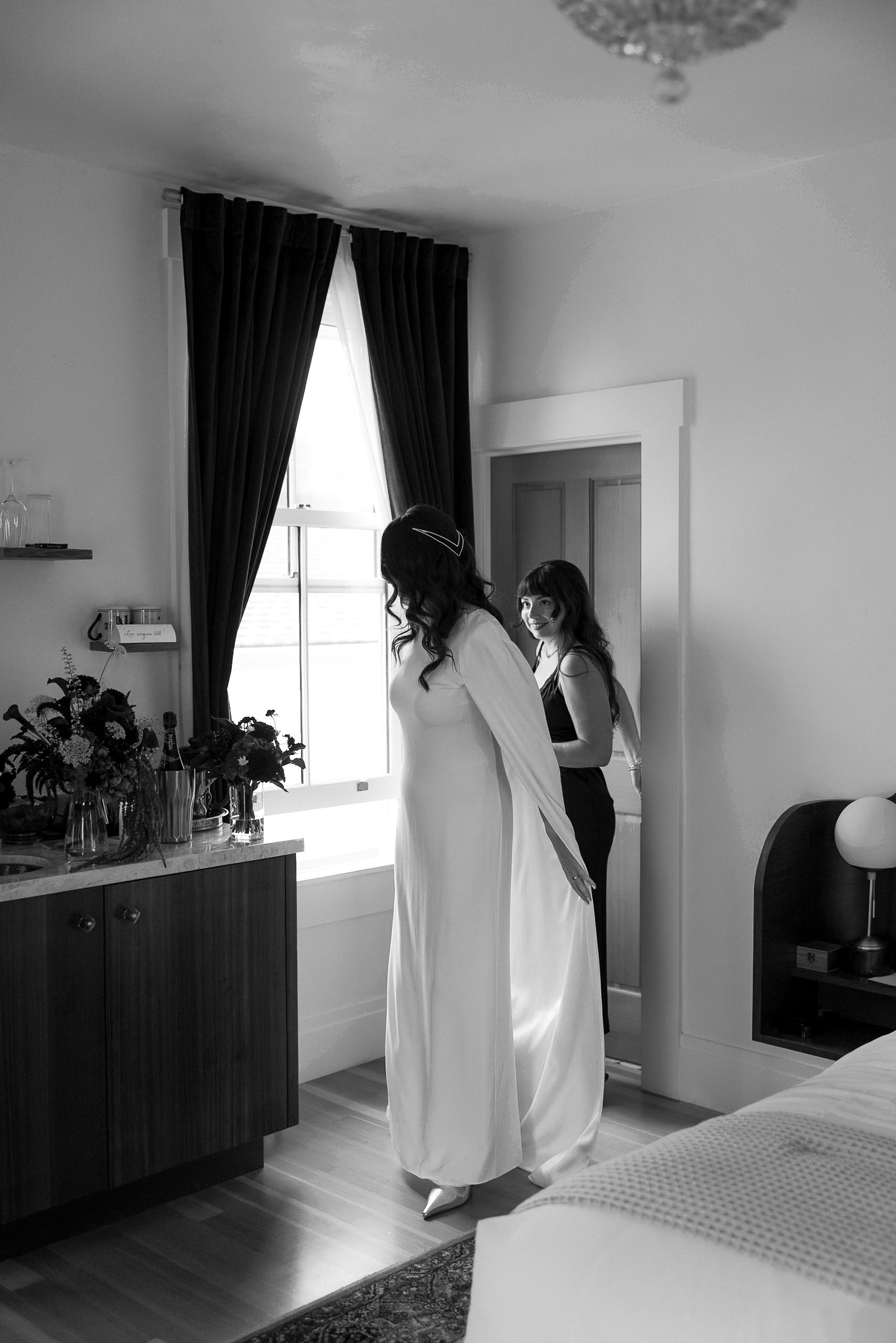 Timeless Bridal Elegance: Black & White Portrait in Mendocino with Bridesmaid Adjusting Gown.