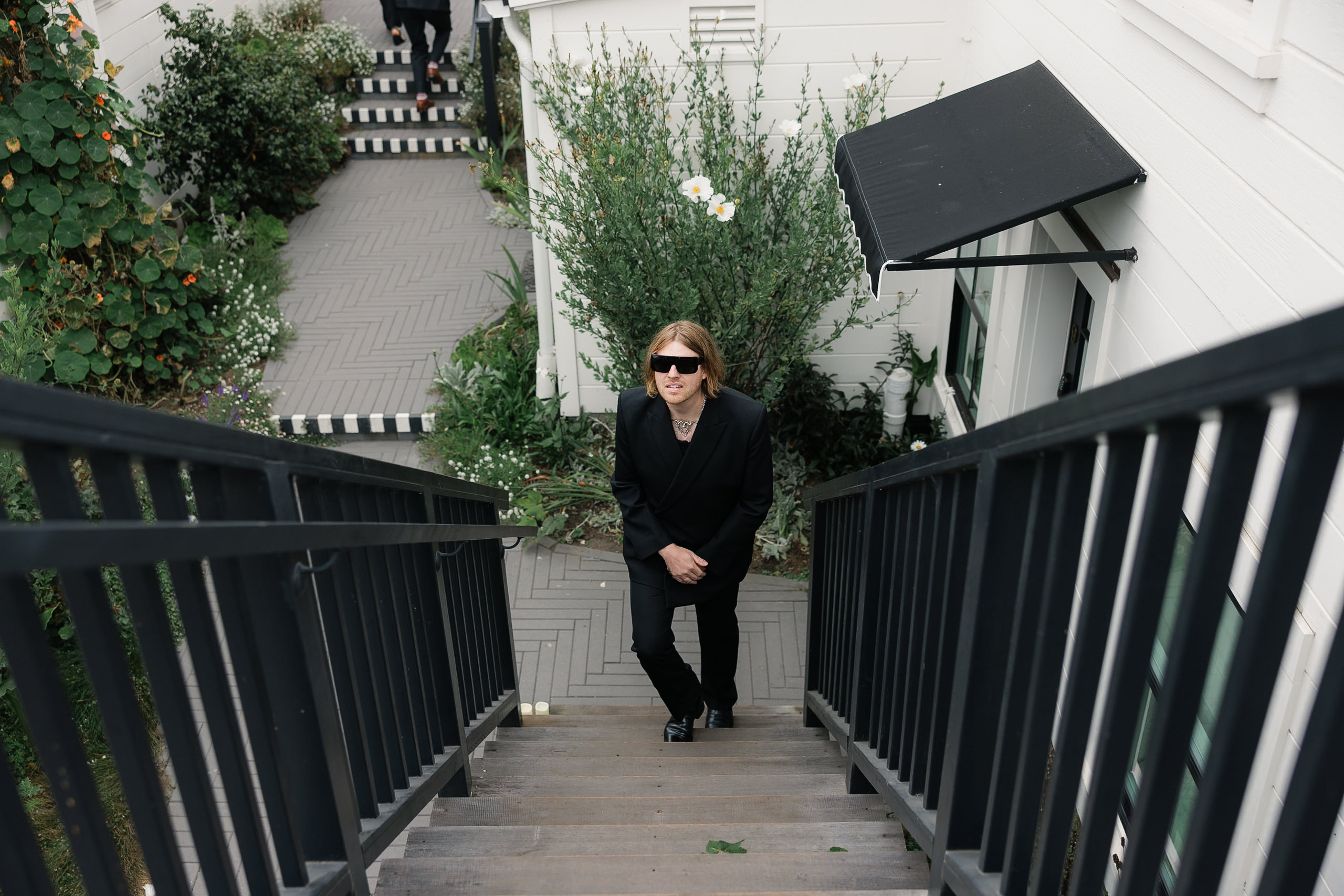 Elegant Portrait on Mendocino Staircase: Black Attire, Greenery & White Architecture Elements.