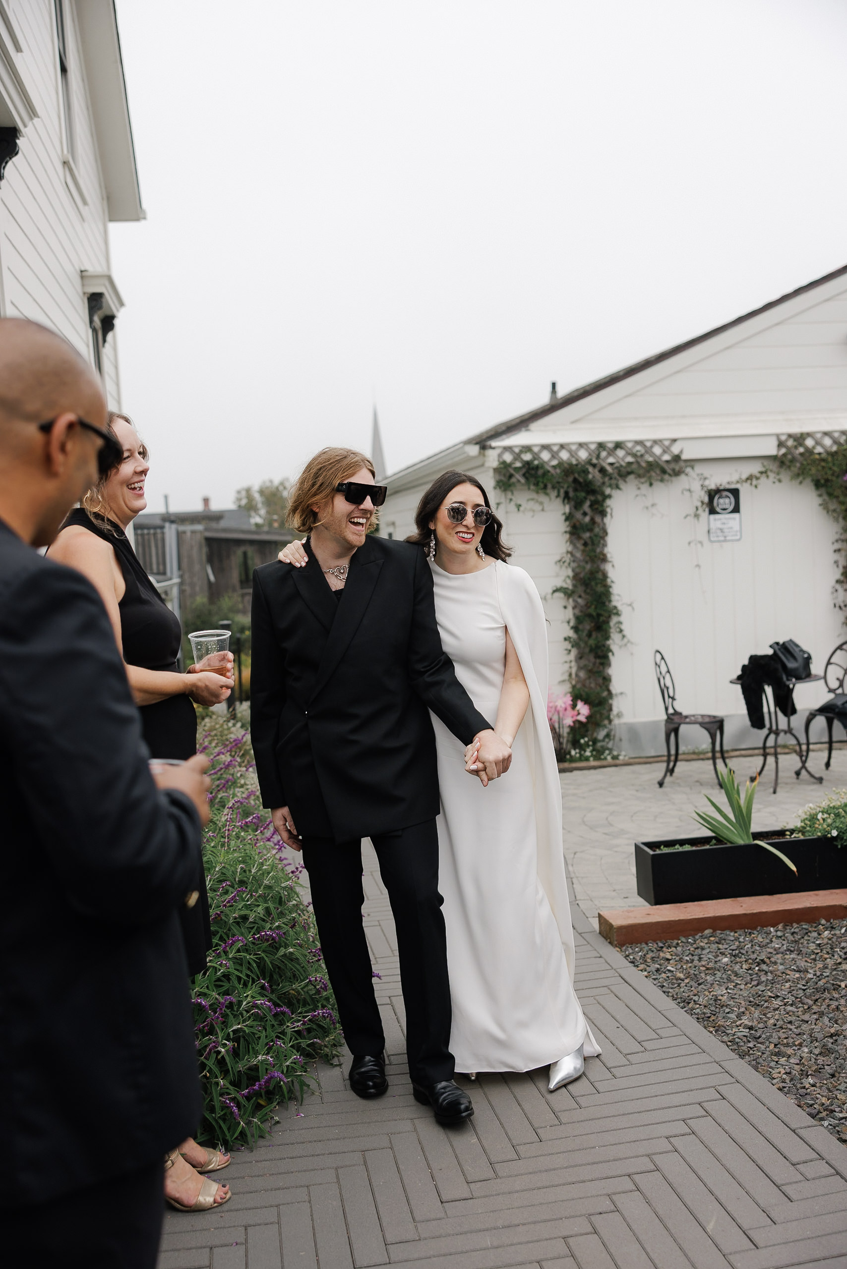 Elegant couple in formal black and white attire walking through Mendocino, captured by top wedding photographer.