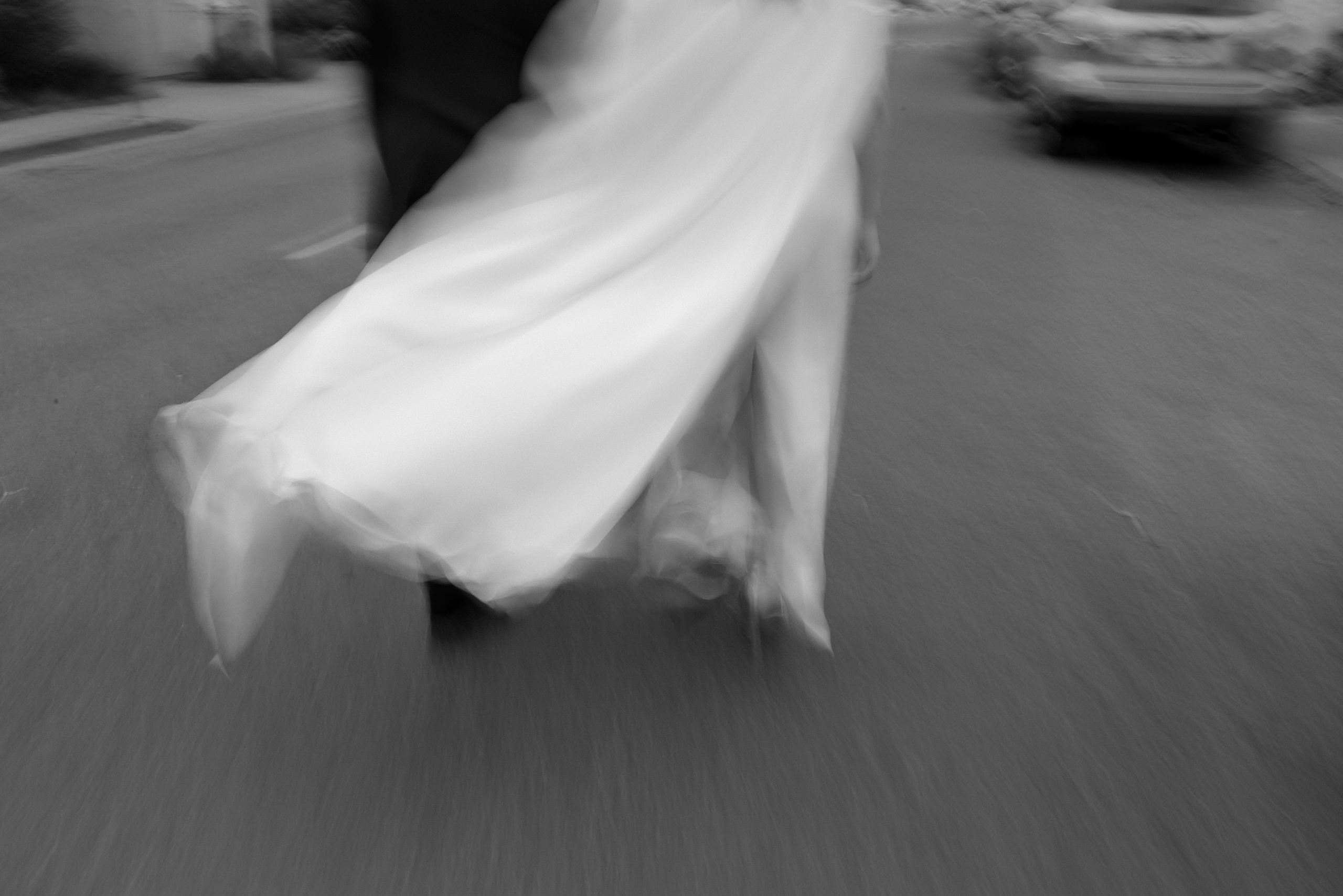 Timeless black-and-white portrait: couples wedding stroll in Mendocino street, dress billowing beautifully.