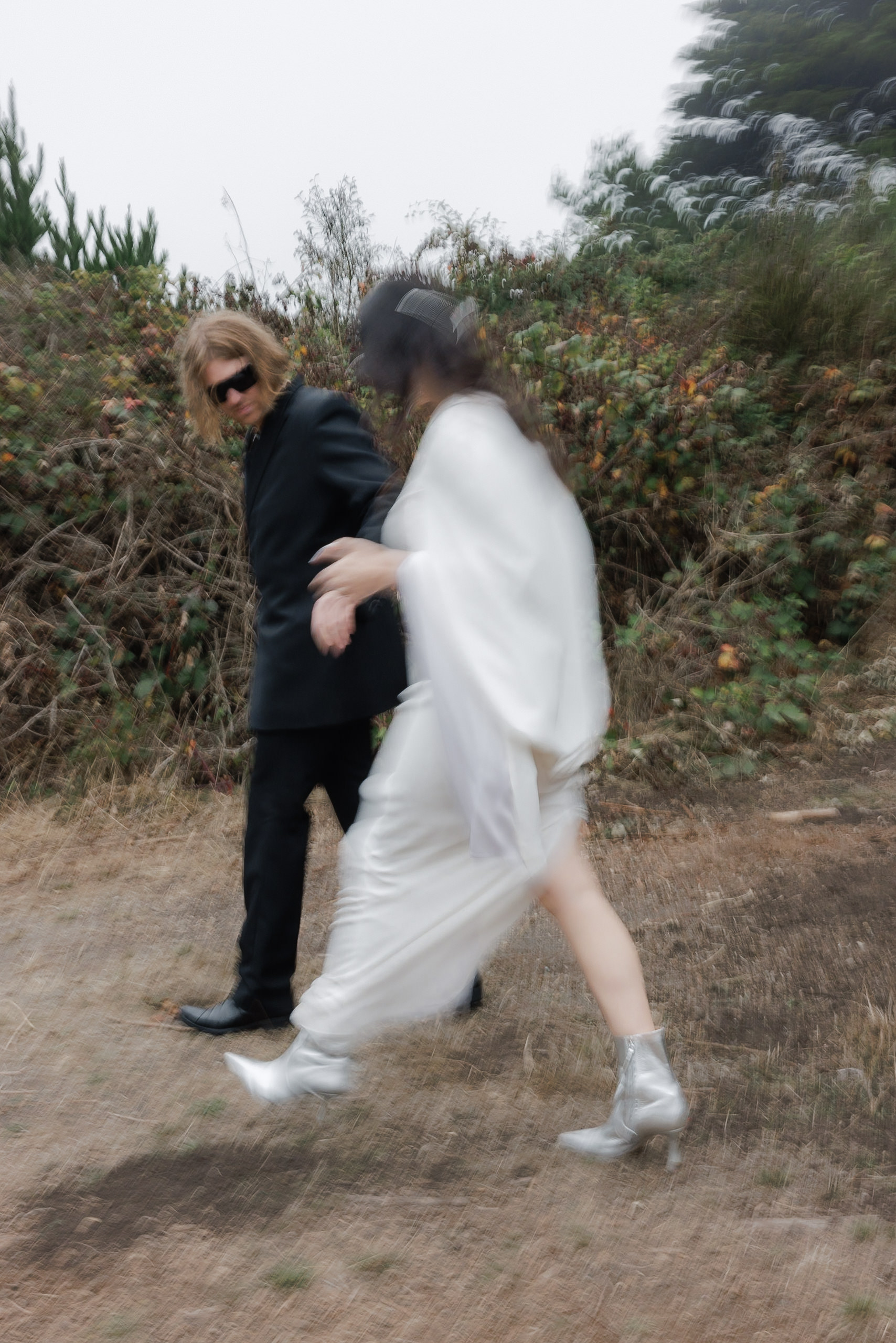 Capture motion and elegance in Mendocino: Black-suited figure with bride in white gown and silver boots.