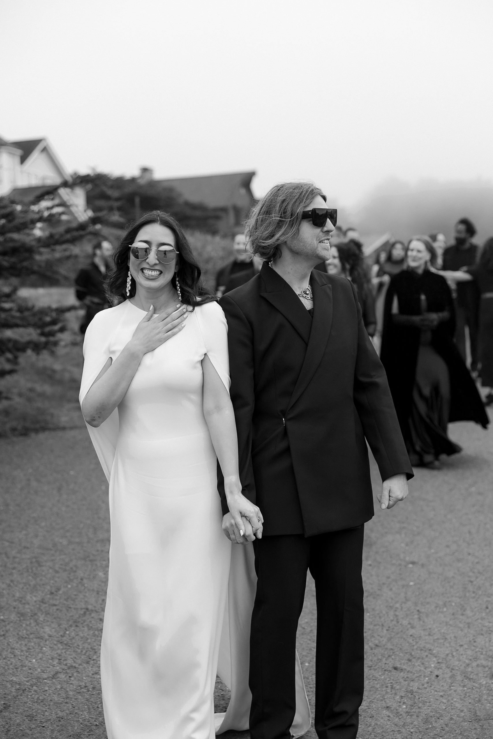 Elegant Mendocino wedding photography: a couple in formal attire strolls amidst a classic black-and-white setting.