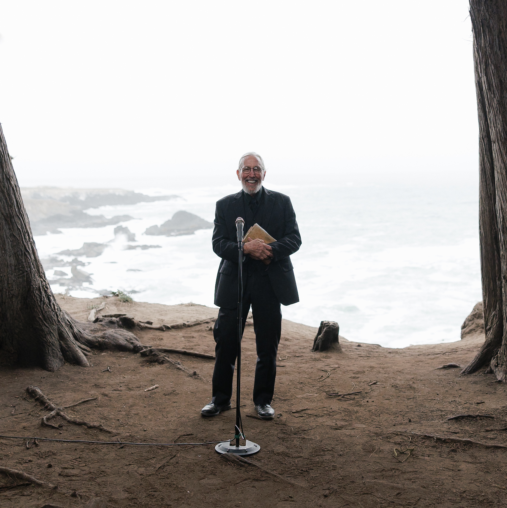Elderly man smiling at outdoor wedding, Mendocino Coast backdrop with ocean views.