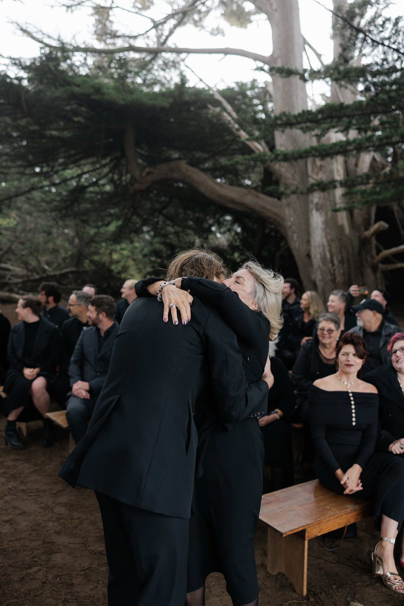 Elegant embrace under Mendocinos majestic trees at a serene outdoor gathering.