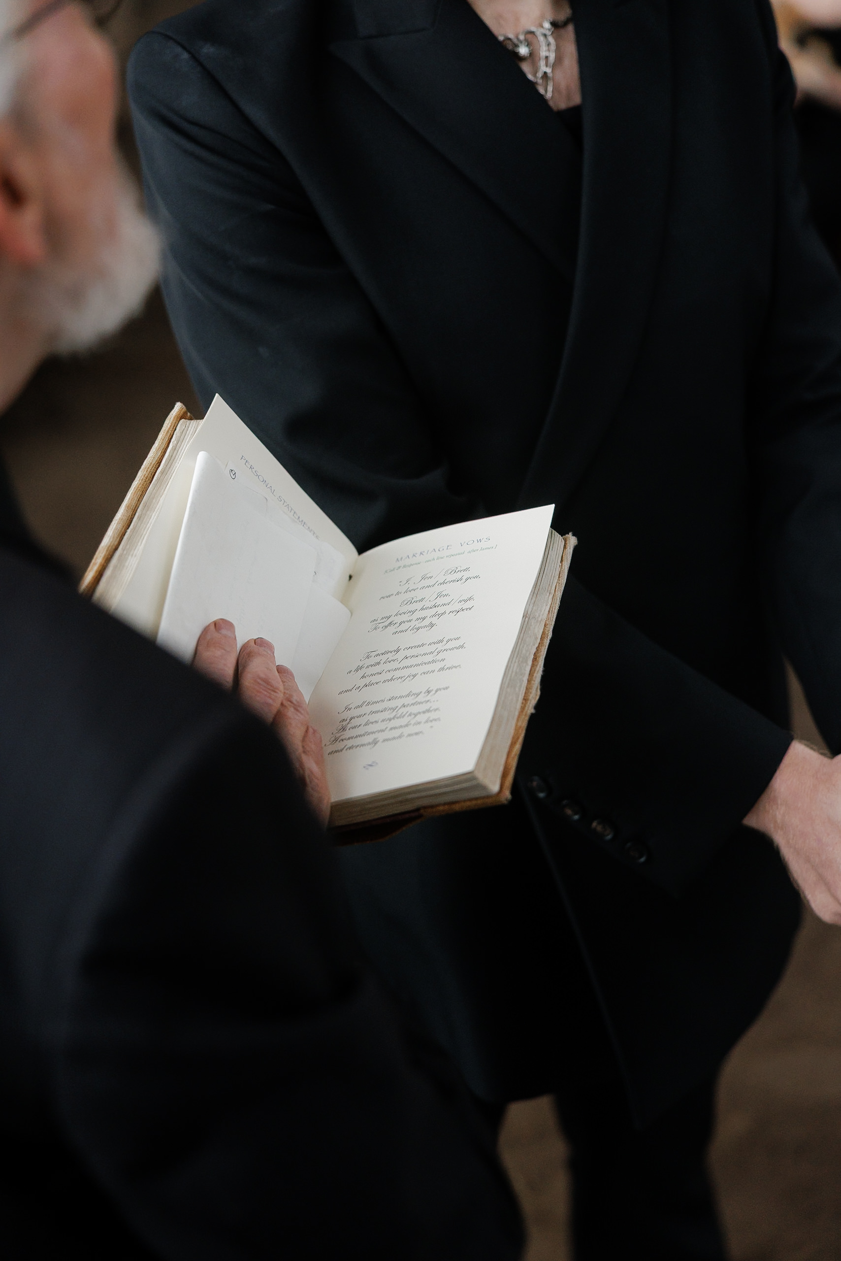 Elegant Black-Tie Couple Engaged with Mendocino-Themed Book – Detailed, Hands-Focused Wedding Photography.