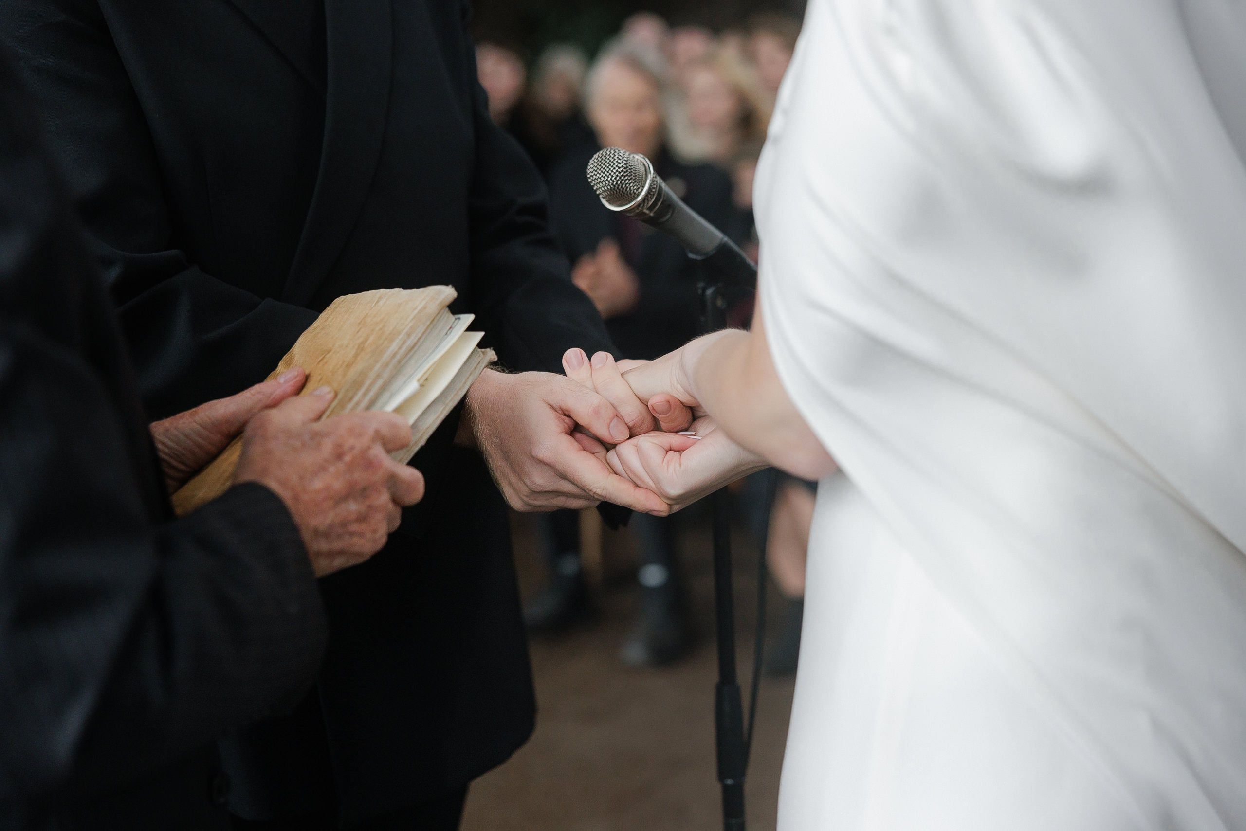 Mendocino wedding ceremony: Bride and groom hand-in-hand; officiant stands ready with vows.