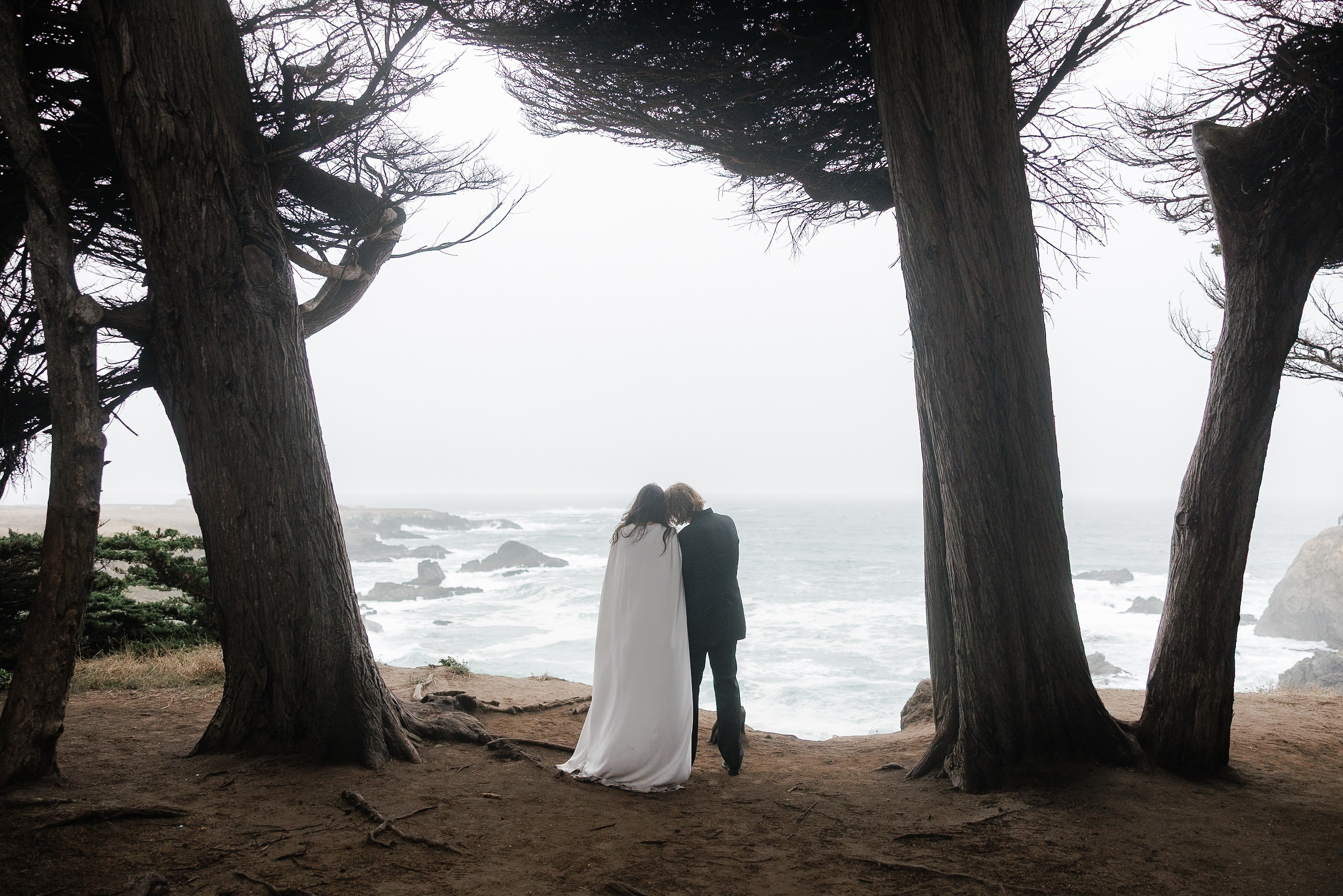 Mendocino wedding photography: Couple on cliffside with ocean view, capturing misty romantic scenery.