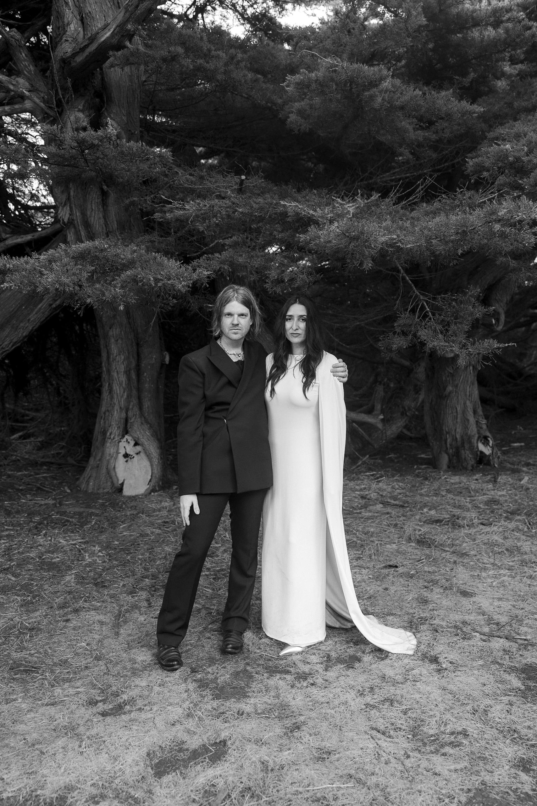 Elegant couple framed by Mendocinos majestic trees in timeless black & white wedding portrait.