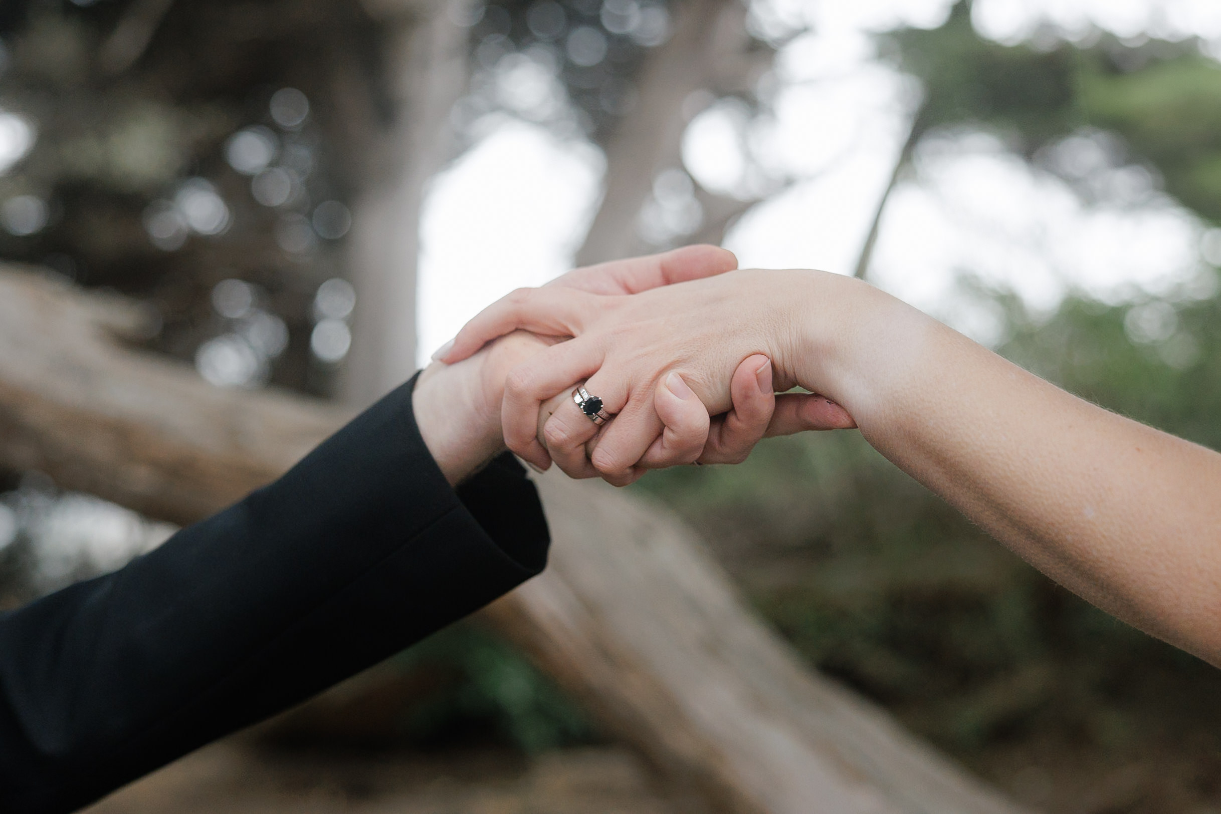 Elegant engagement shot: Couples hands intertwined in Mendocino forest - ring detail.