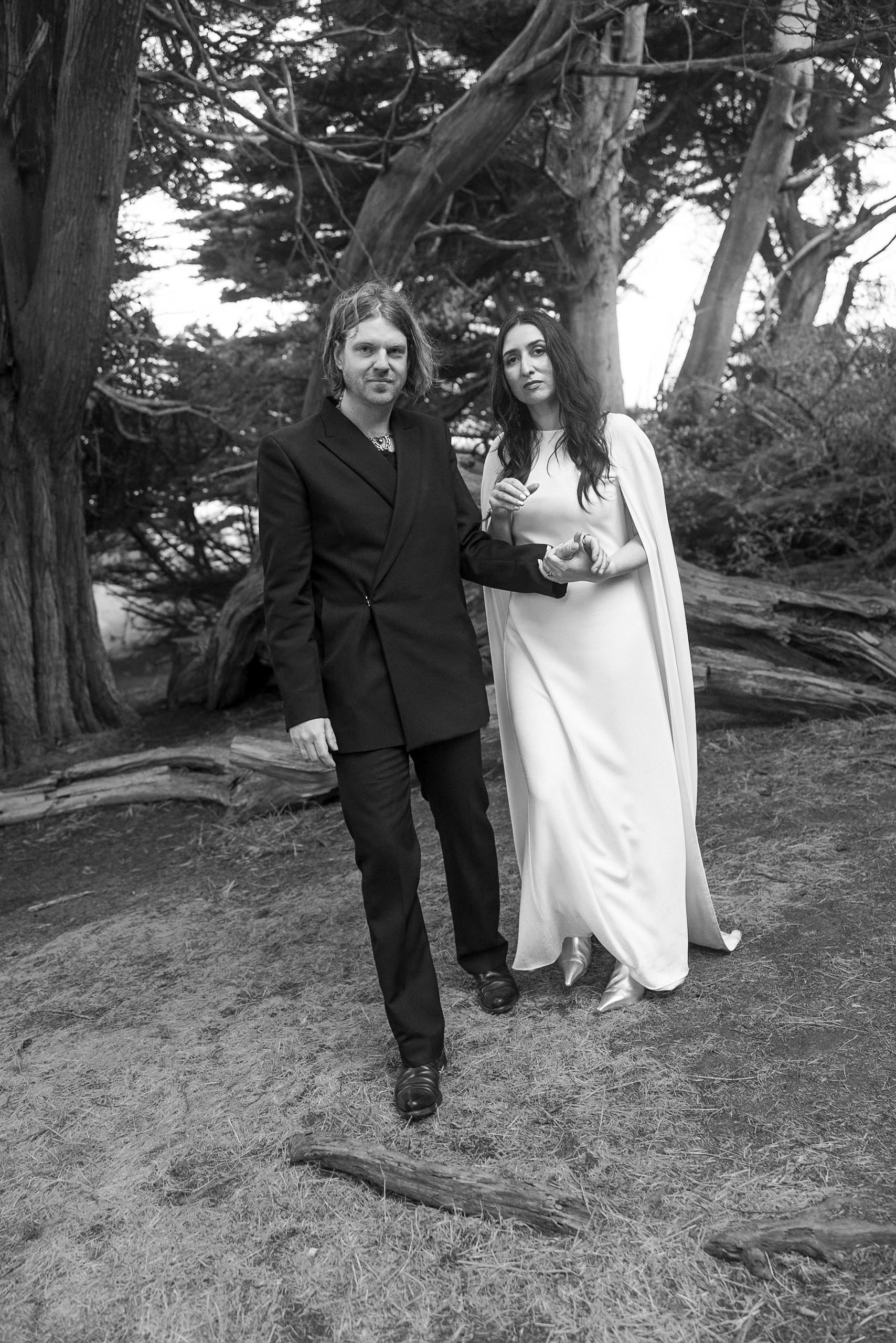 Elegant Mendocino wedding: couple in black-and-white stroll through wooded landscape.