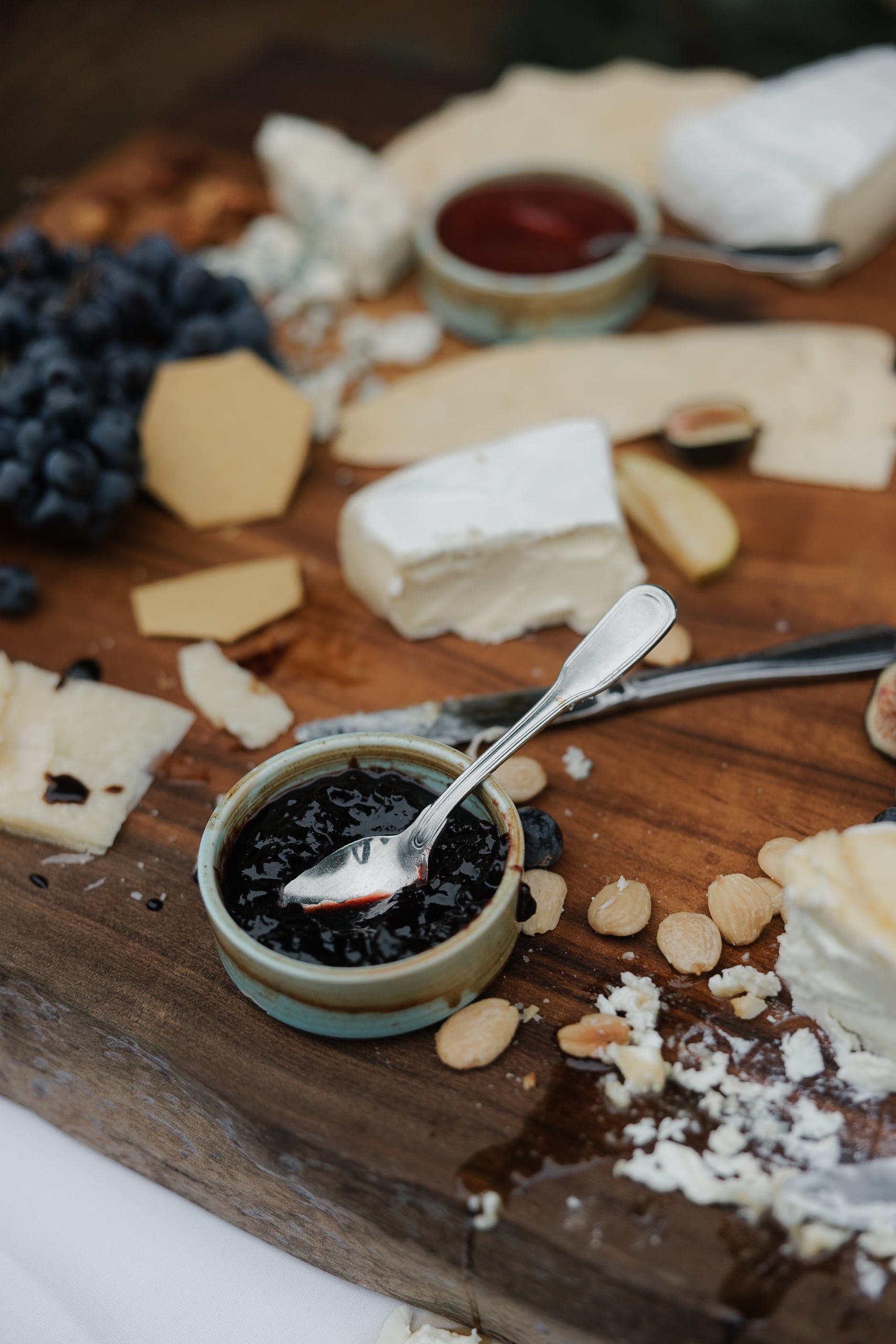 Elegant charcuterie board with cheeses, baguette, grapes, almonds; Mendocino picnic charm. Ideal wedding shot.