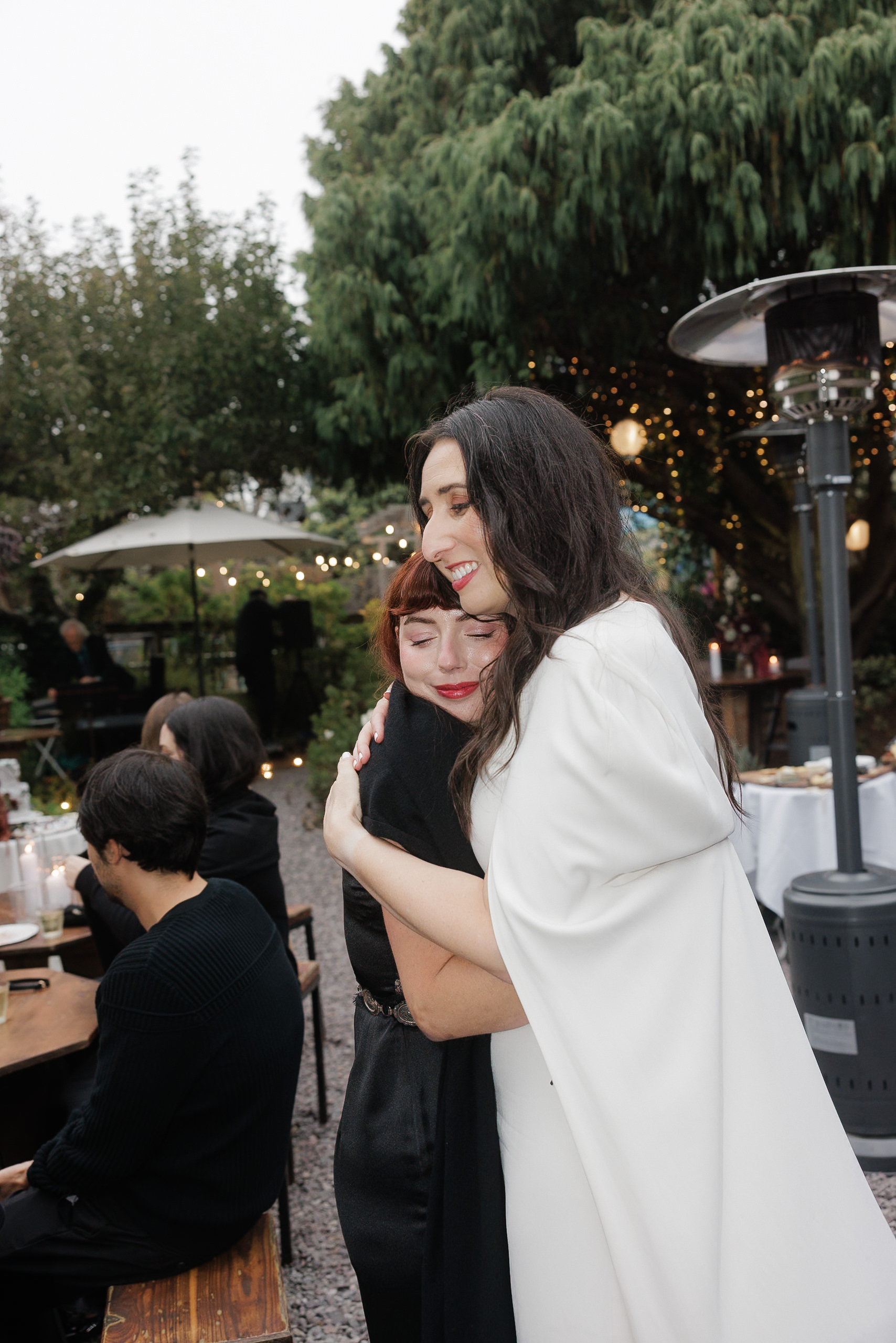 Enchanting Festive Gathering: Smiling Couple in Mendocino Surrounded by Lights and Nature.
