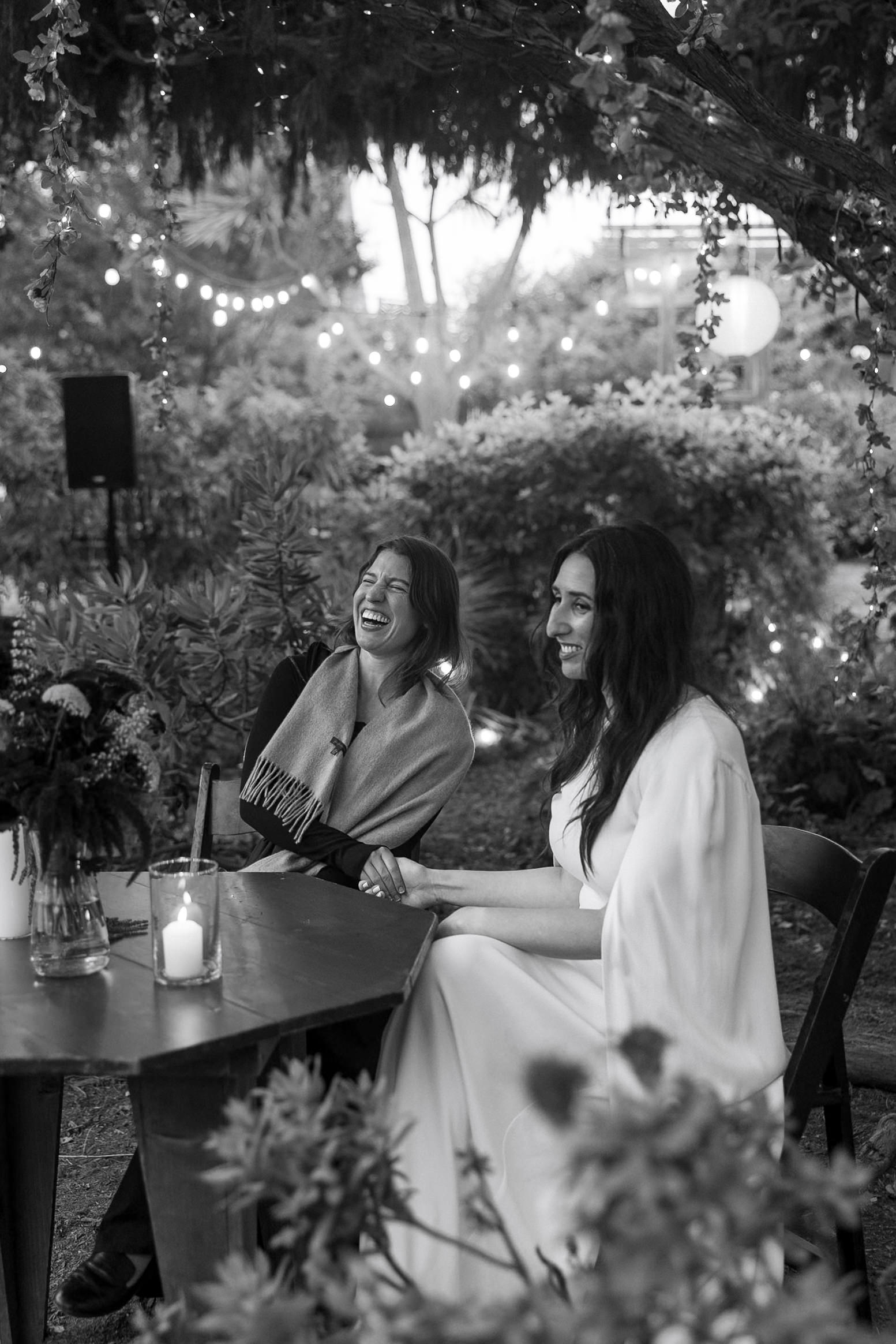 Intimate black-and-white photo: two women under Mendocino lights, smiling and holding hands.