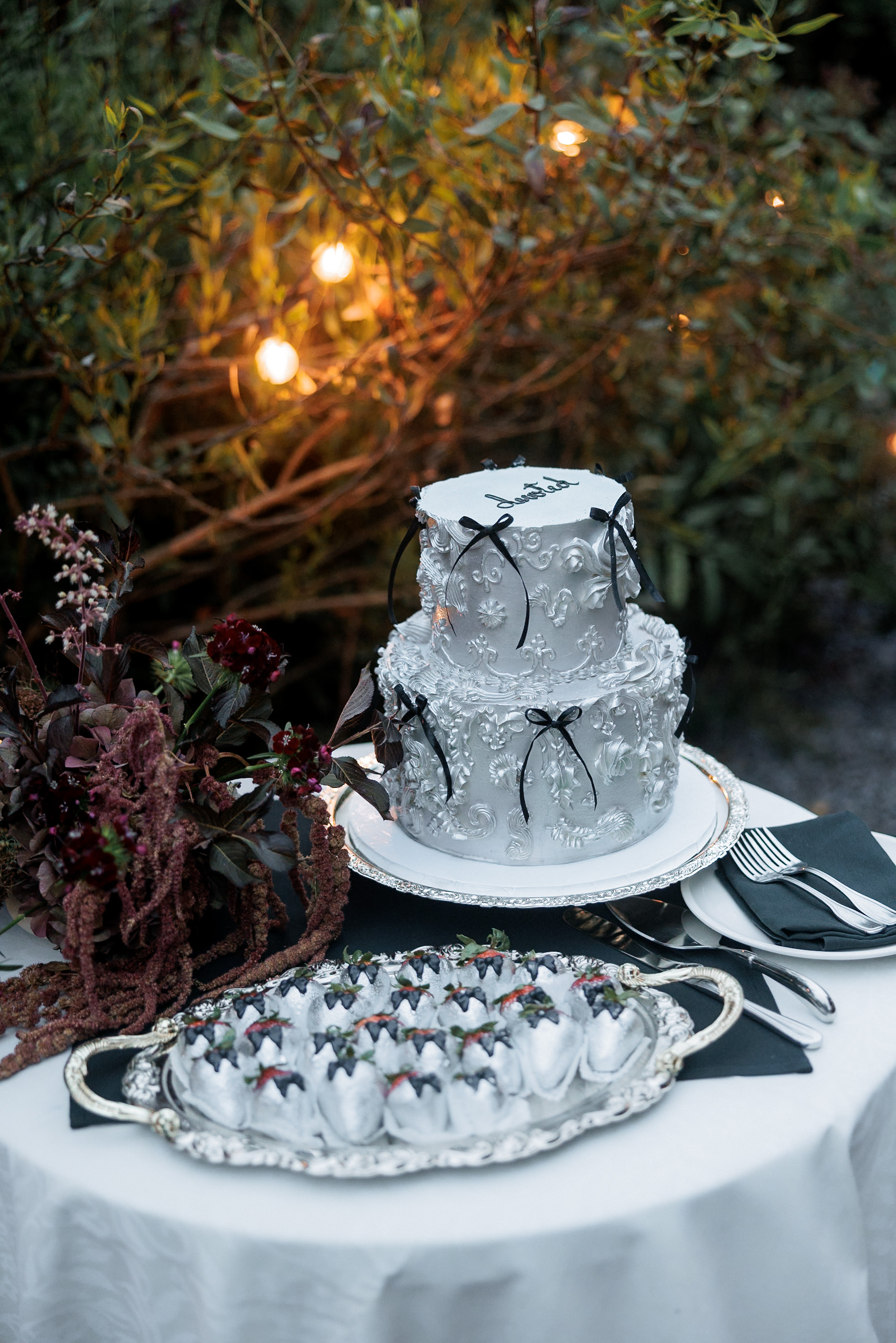 Elegant two-tiered white wedding cake with floral icing, black bows, and Mendocino charm.