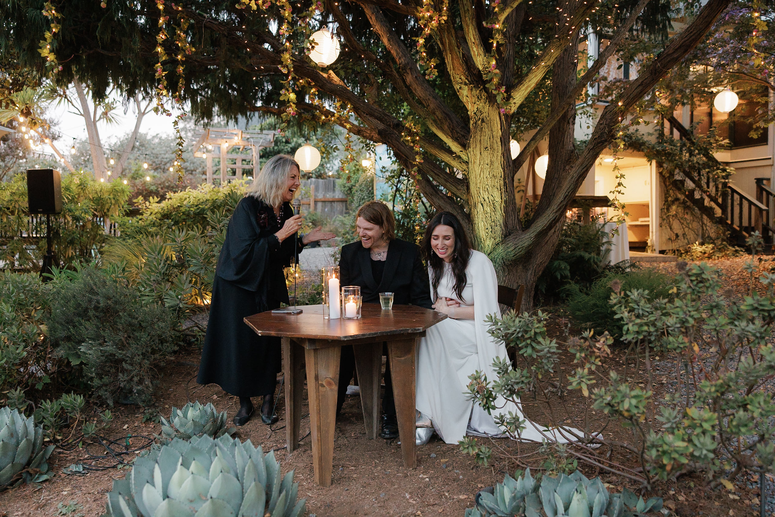 Elegant outdoor wedding photography in Mendocino: Candid moments under a lit tree canopy.