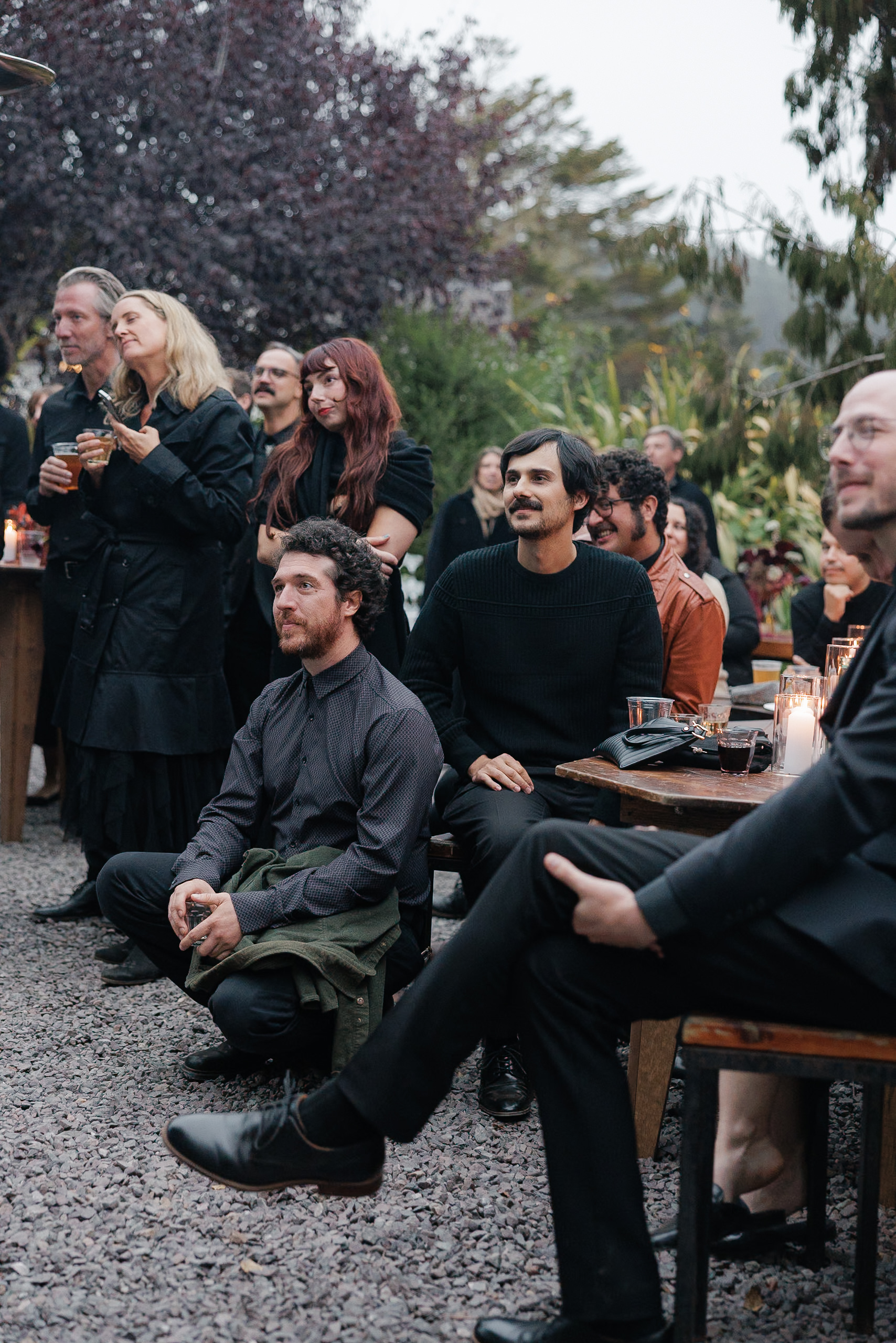 Mendocino Wedding: Guests seated on gravel, surrounded by lush greenery and trees.