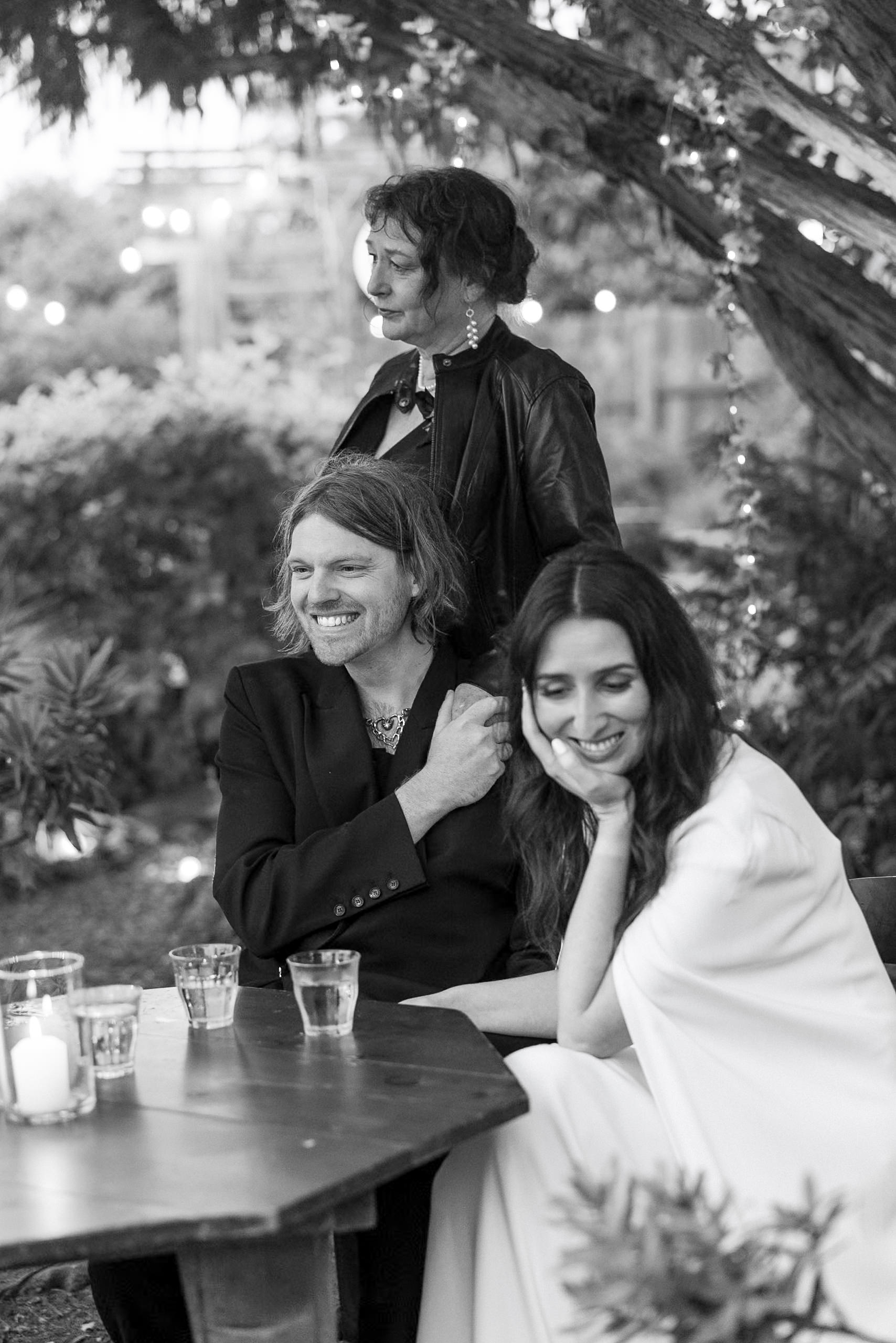 Elegant outdoor Mendocino gathering: Stylish trio in a serene, natural setting at a wooden table.
