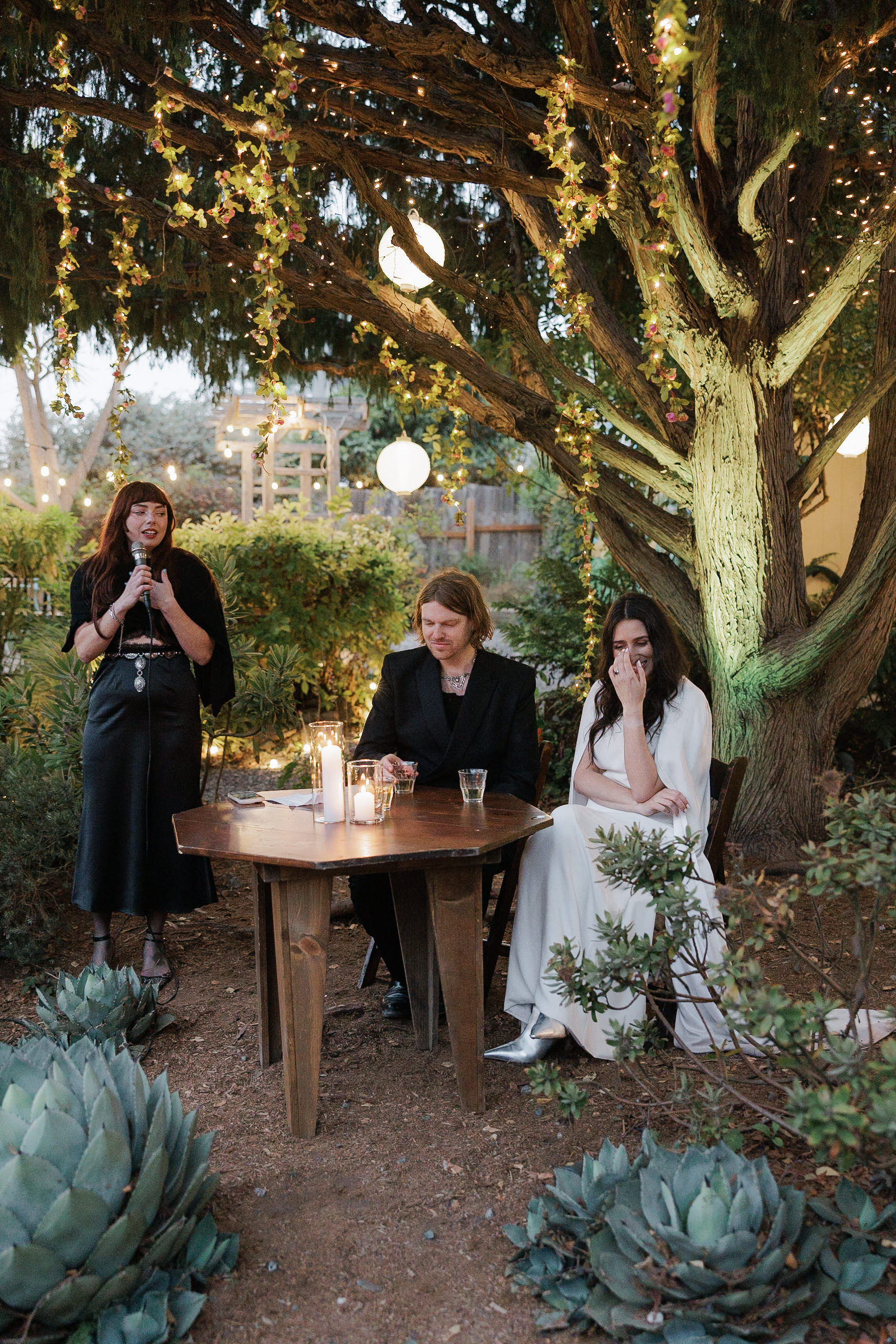 Elegant outdoor wedding in Mendocino: Tree lights, candles, and lush greenery evoke a serene atmosphere.