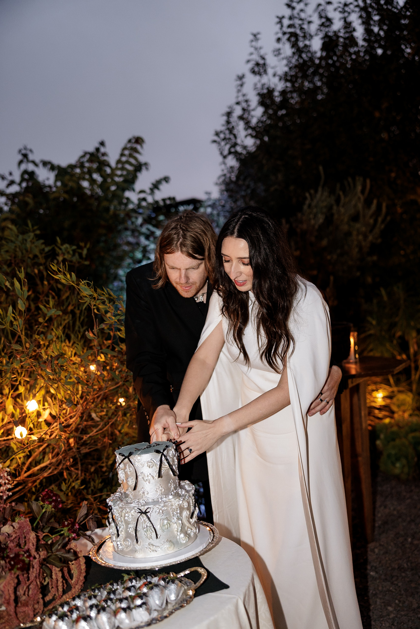 Capture the essence of luxury amidst Mendocinos greenery: a couples cake-cutting moment in elegant attire.