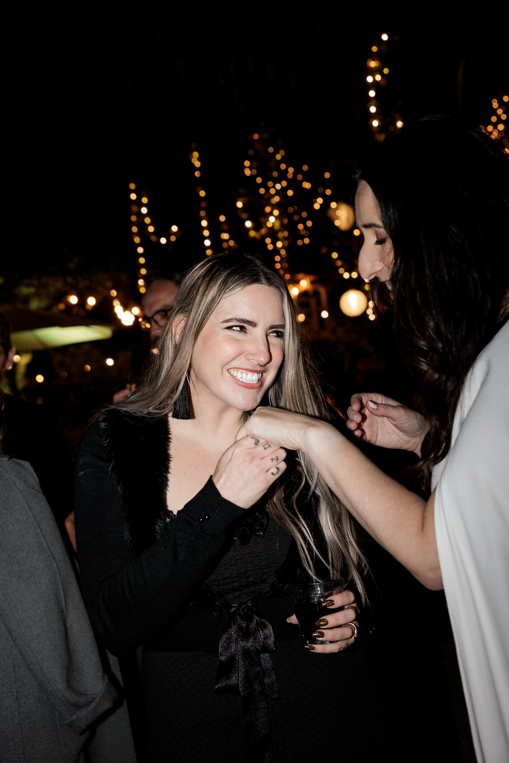 Elegant evening wedding in Mendocino: two women, glowing under string lights, share a joyful moment.