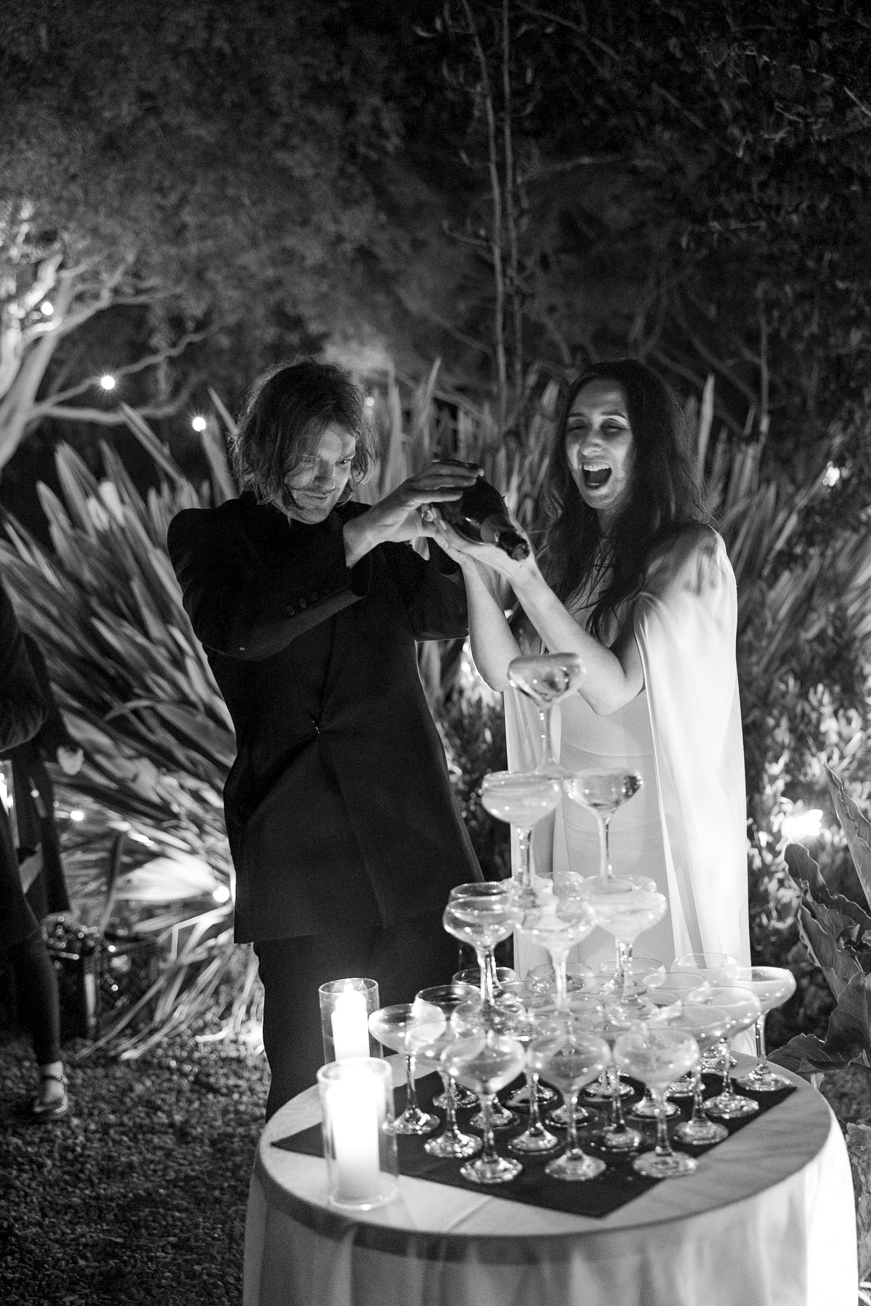 Stunning Black & White Mendocino Wedding: Couple Celebrates with Champagne Tower in Elegant Outdoor Setting.