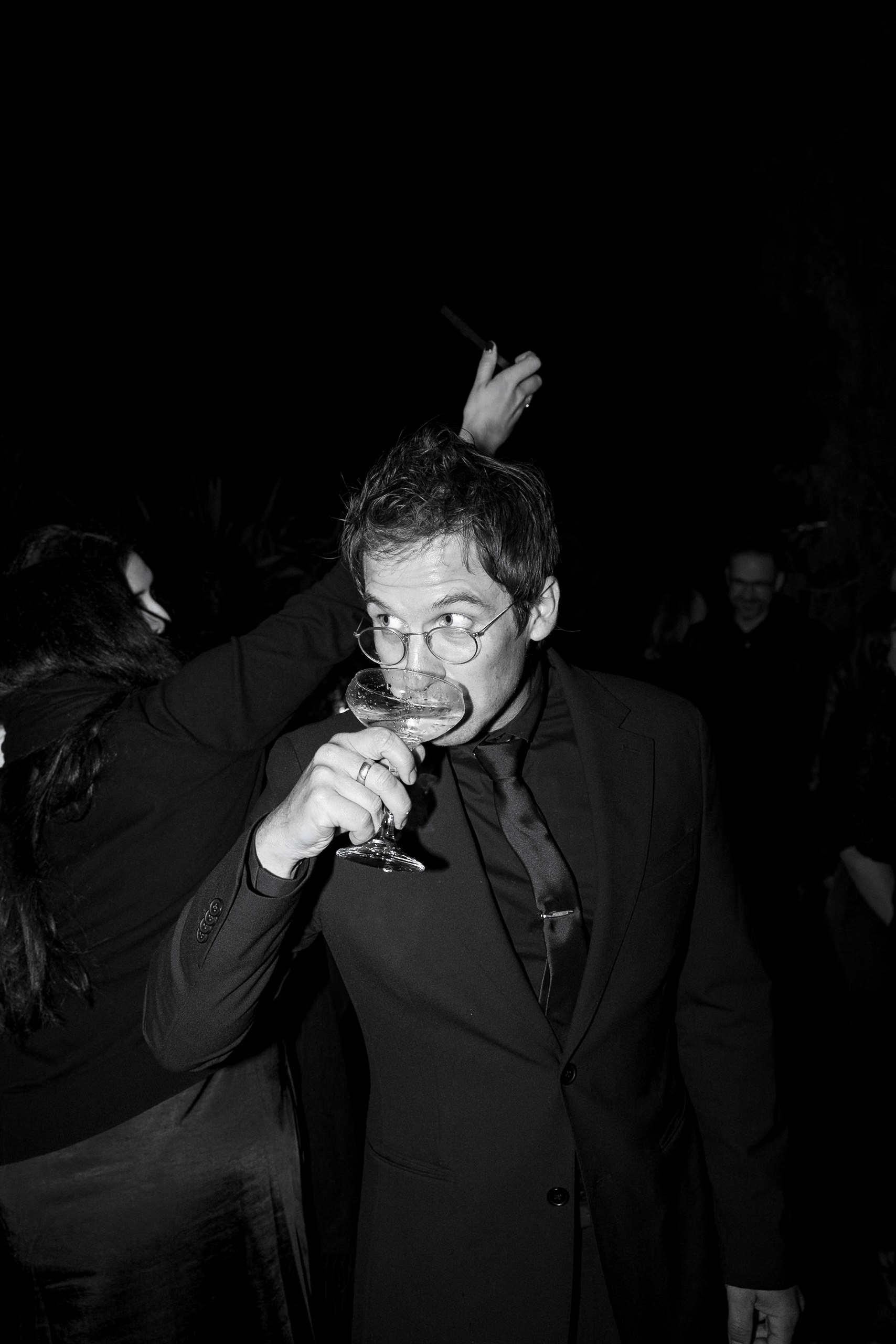 Elegant black-and-white wedding celebration in Mendocino; guest toasting in formal attire.