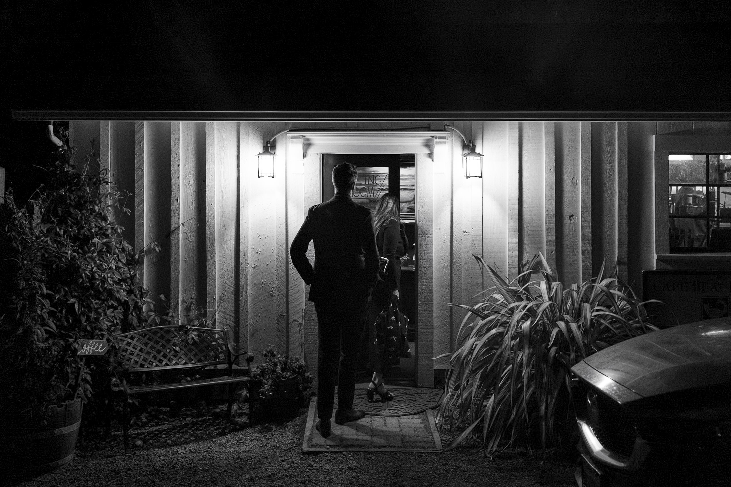 Black-and-white Mendocino wedding silhouettes at night, featuring cozy bench and lush plants.