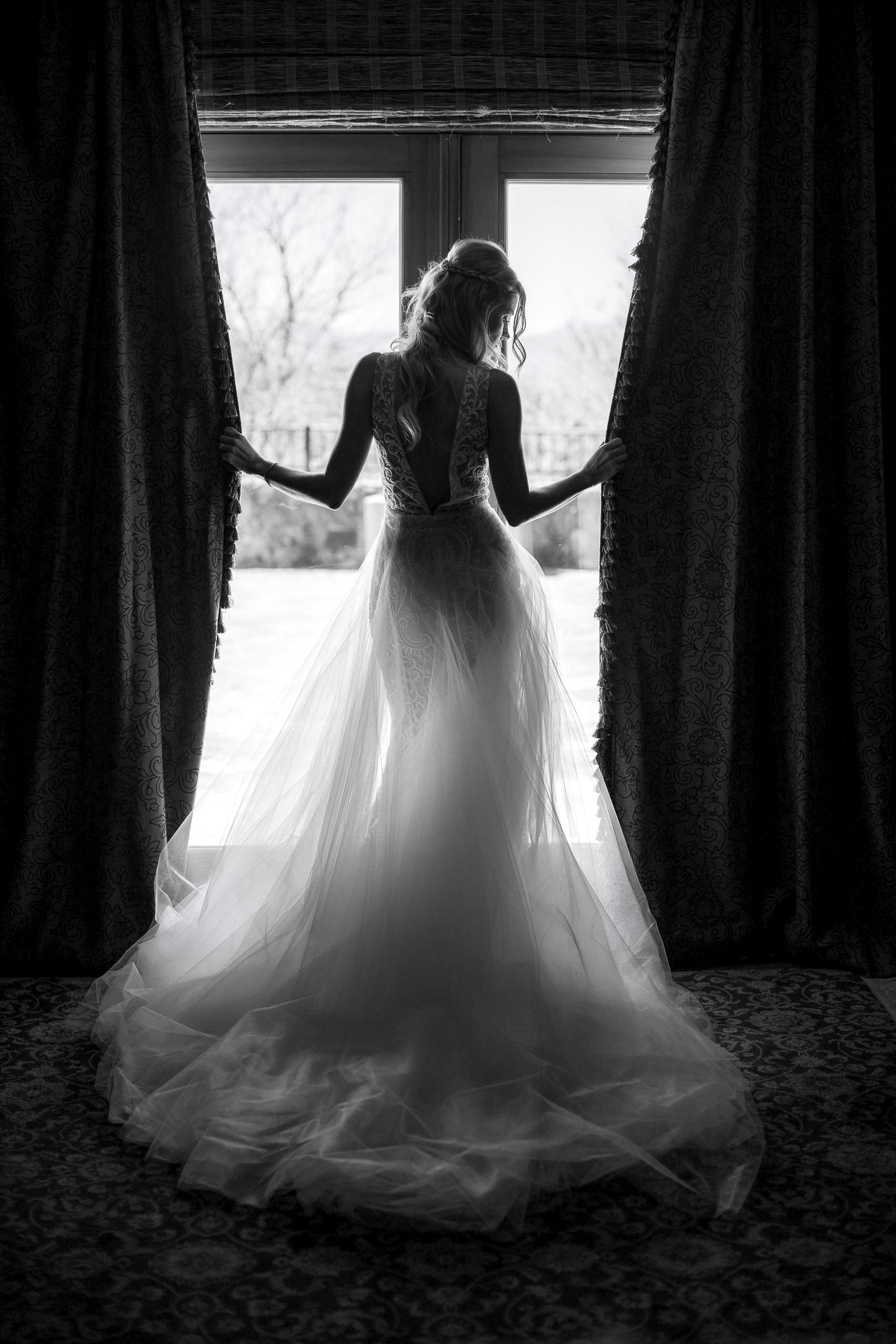 Silhouette of bride in lace gown by sunlit window, evoking Napa Valley serenity.