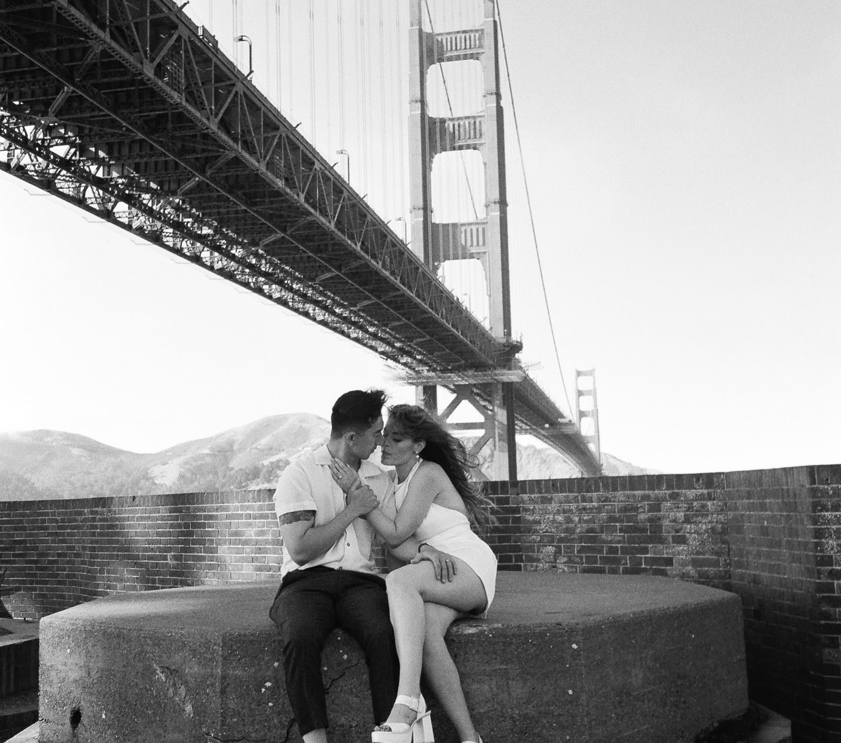 Black & white couple portrait under Golden Gate Bridge; elegant, romantic wedding photography.