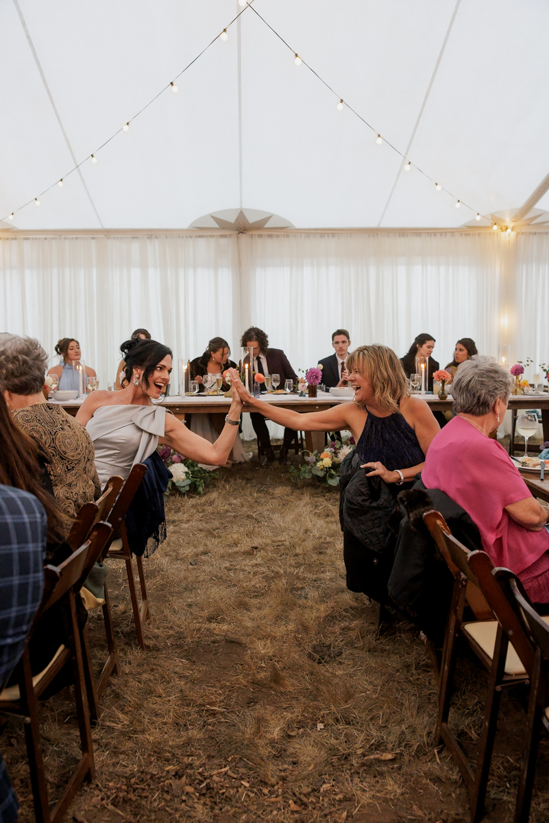 Joyful High-Five at Elegant Wedding Reception Under String Lights.