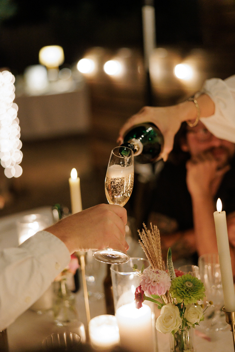 Elegant champagne pour at romantic, candlelit dinner—floral decor, warm glow captures celebration.
