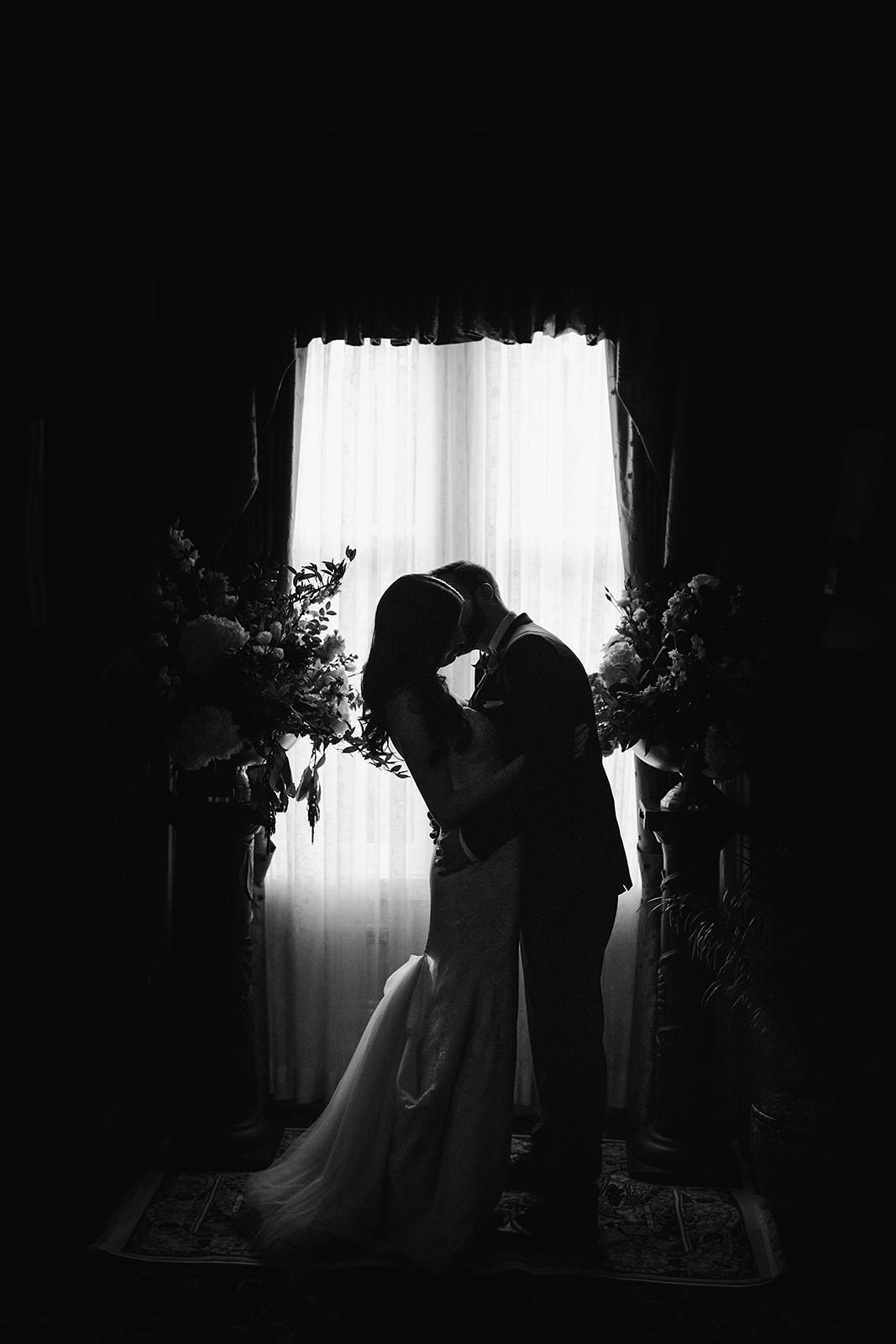 Silhouetted couple kissing in Healdsburgs Madrona Manor, highlighted by elegant floral decor and romantic lighting.