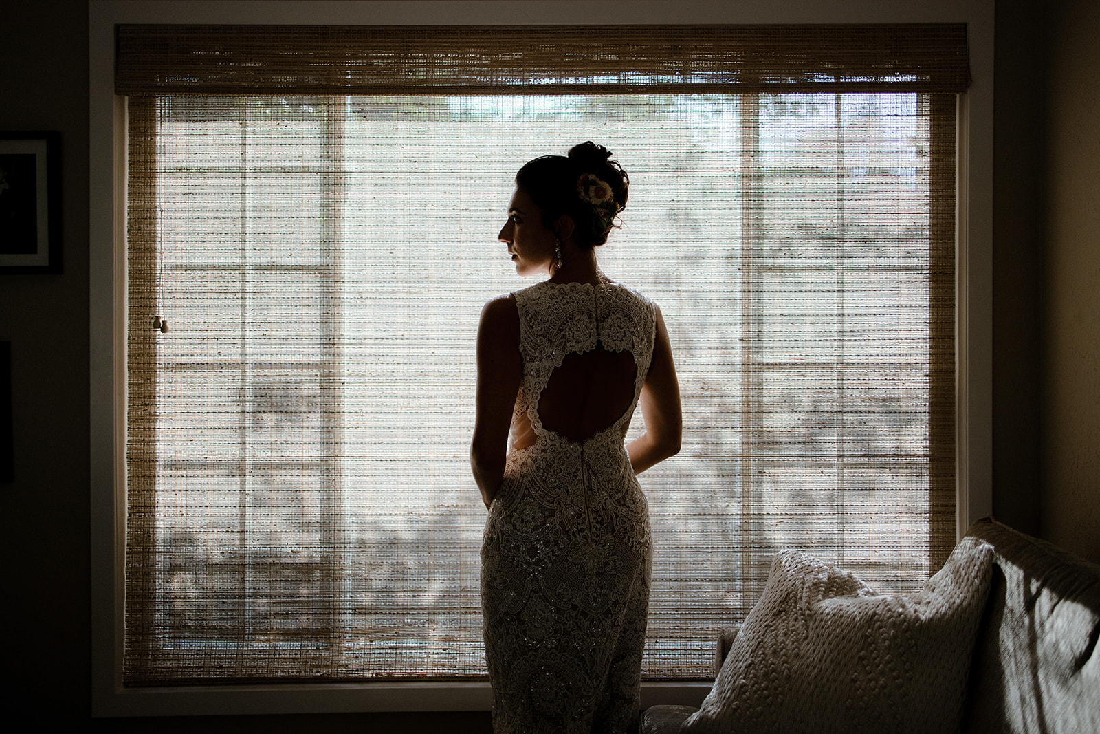 California Bride in Lace Dress: Sunlit Elegance & Floral Updo by Window with White Decor.